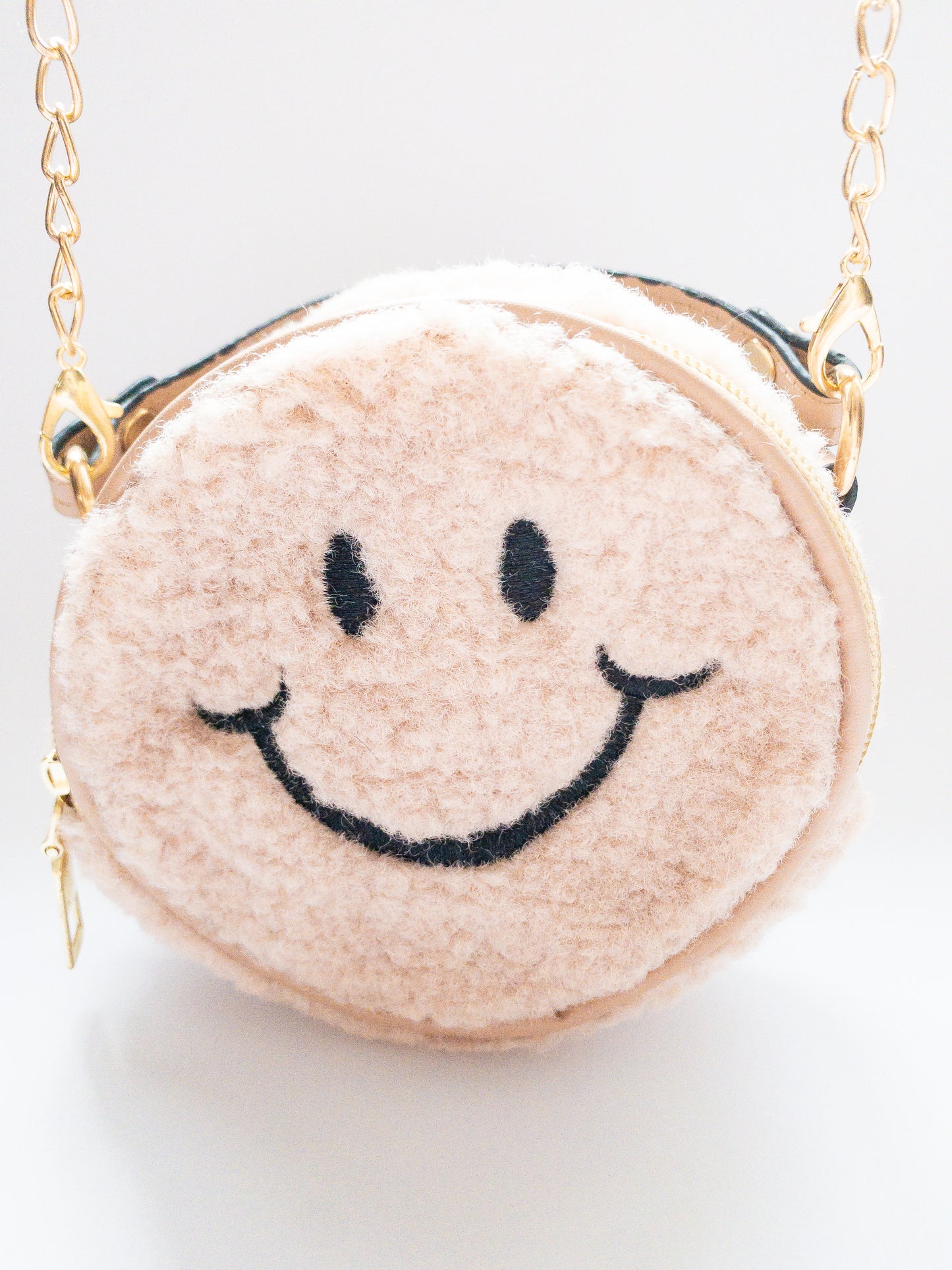 The cutest smiley face bag! This little purse is fuzzy and happy with a single zip open. It has a small open pocket in the back and a short vegan leather handle. The gold chain strap is removable. Choose from 3 cute colors.