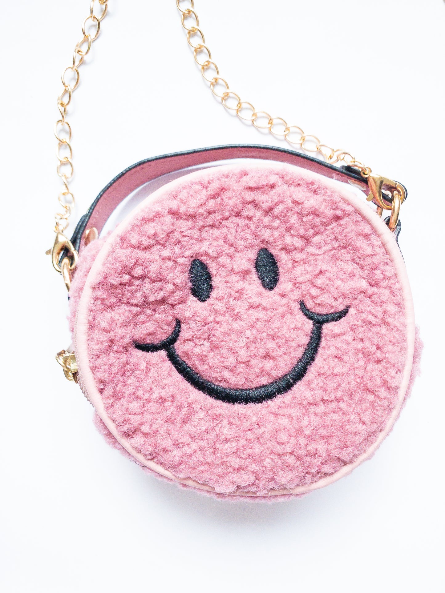 The cutest smiley face bag! This little purse is fuzzy and happy with a single zip open. It has a small open pocket in the back and a short vegan leather handle. The gold chain strap is removable. Choose from 3 cute colors.