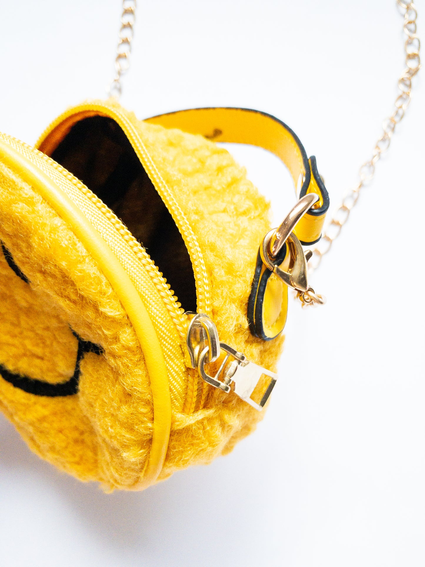 The cutest smiley face bag! This little purse is fuzzy and happy with a single zip open. It has a small open pocket in the back and a short vegan leather handle. The gold chain strap is removable. Choose from 3 cute colors.