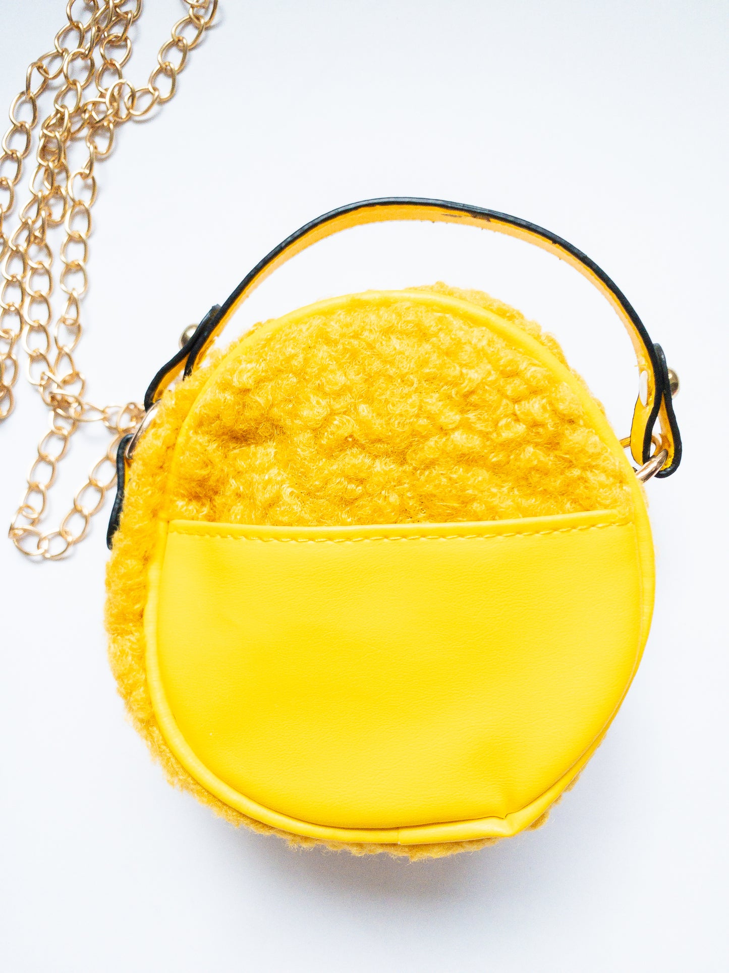 The cutest smiley face bag! This little purse is fuzzy and happy with a single zip open. It has a small open pocket in the back and a short vegan leather handle. The gold chain strap is removable. Choose from 3 cute colors.