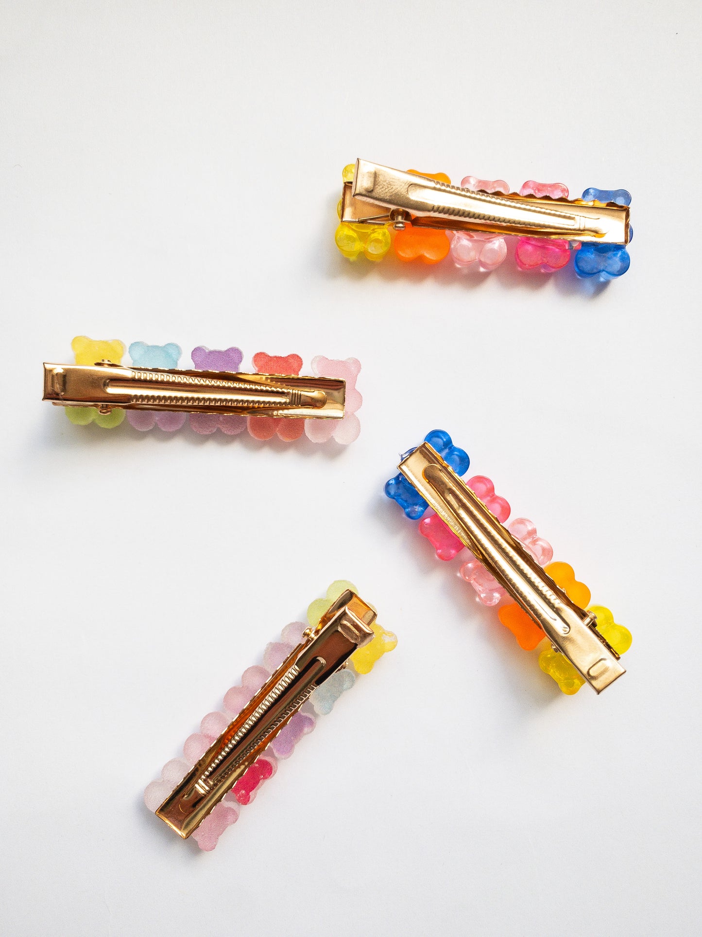 Yummy gummy bear family! The most adorable gummy bear shaped hair clips come as a 4 piece set: two frosted, sugary gummy bears and two translucent rainbow colored gummy bears. Each is on a gold colored alligator clip.