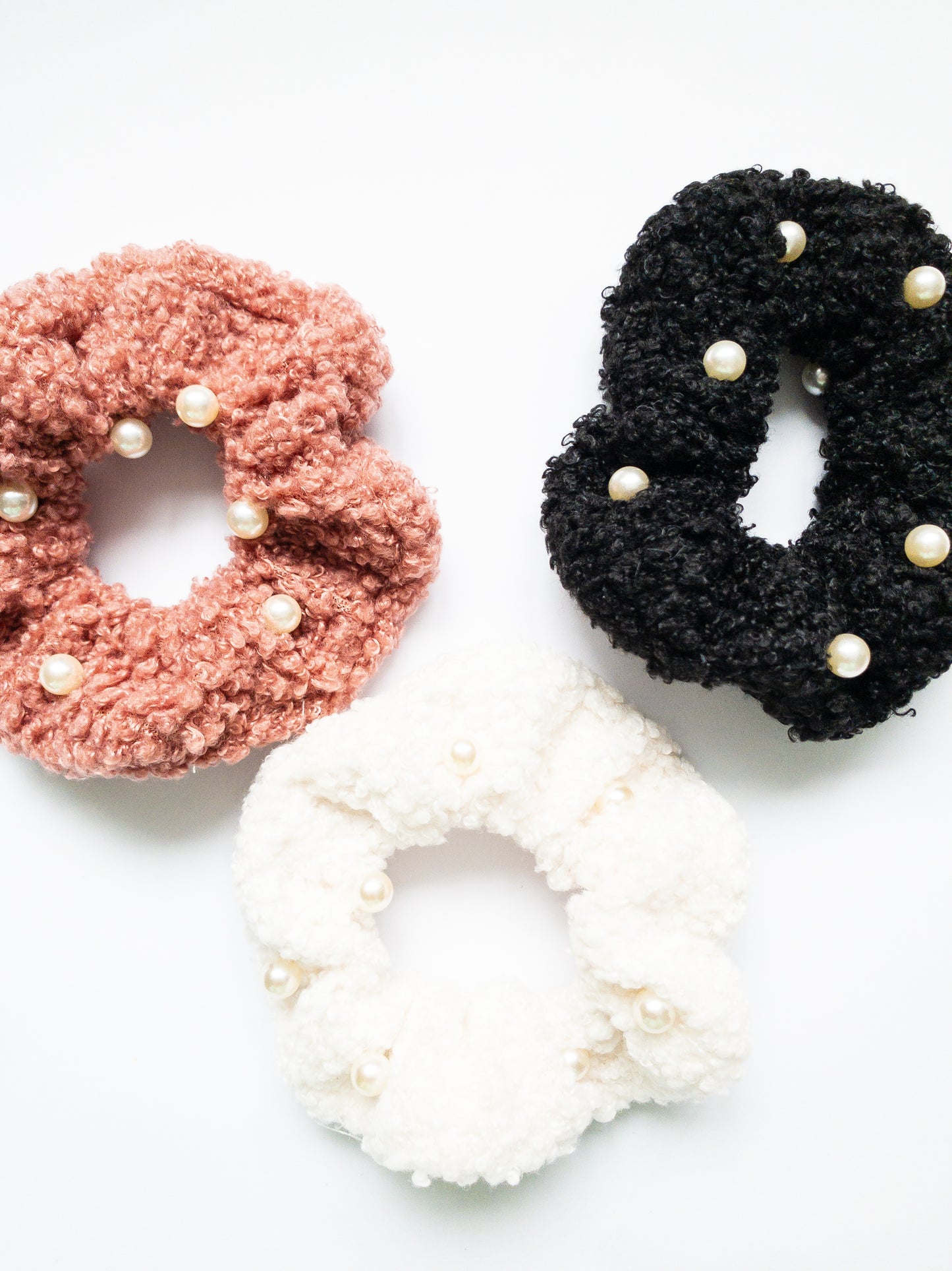 These peppy pearl sherpa scrunchies are so soft and comfy chic! A 3-pack mix of pink, black, and white sherpa and pearls sewn throughout.