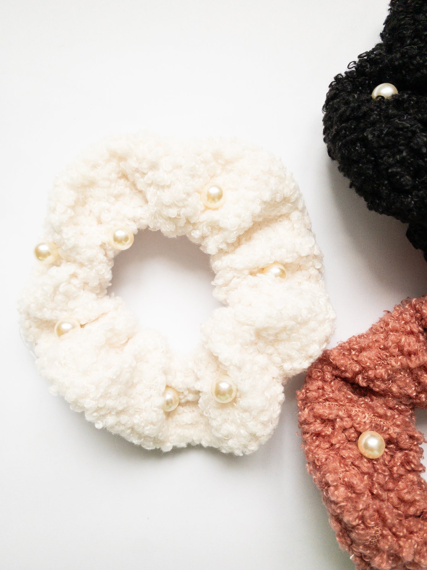 These peppy pearl sherpa scrunchies are so soft and comfy chic! A 3-pack mix of pink, black, and white sherpa and pearls sewn throughout.