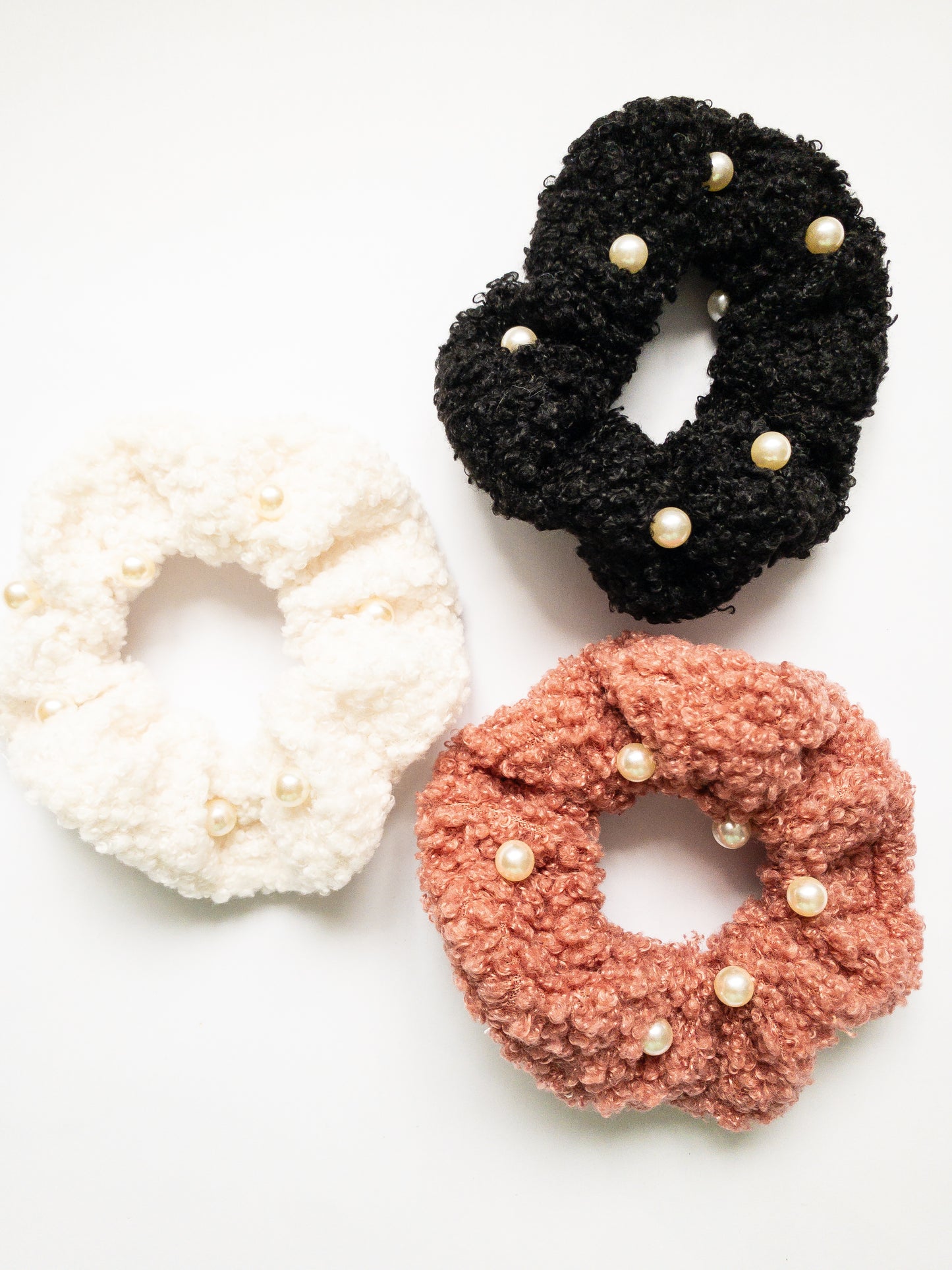 These peppy pearl sherpa scrunchies are so soft and comfy chic! A 3-pack mix of pink, black, and white sherpa and pearls sewn throughout.