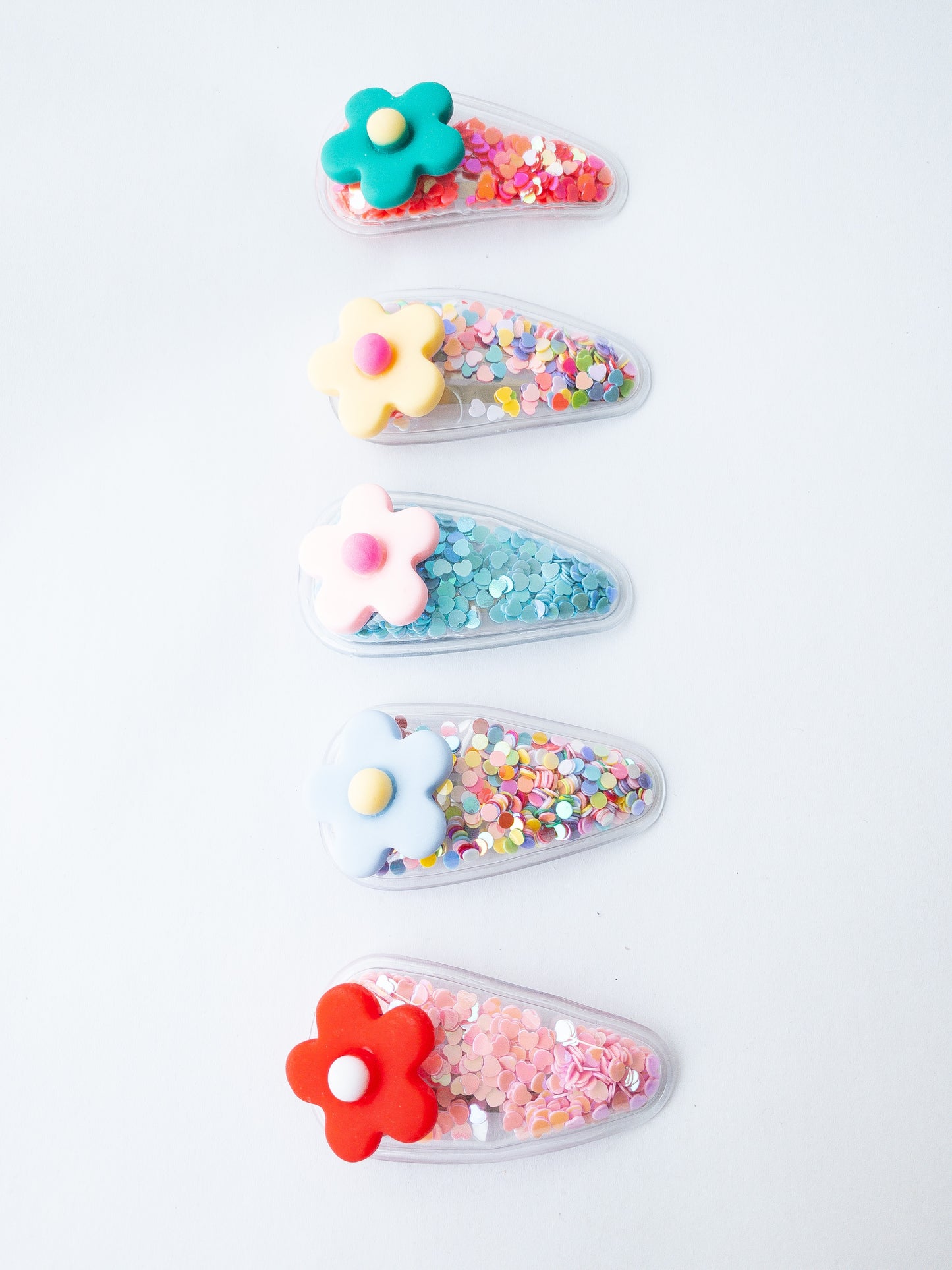 Our signature shaker hair clips but with flowers! Each snap clip is a triangular pouch filled with the most fun confetti--hearts and circles. And to top it all off, there is a pretty flower on the end of each clip. These are sure to make anyone smile!