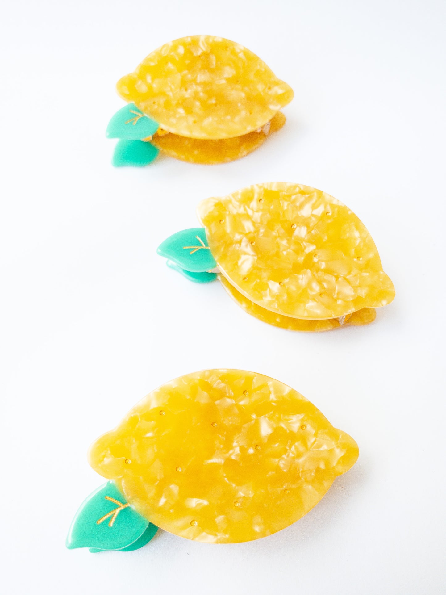 A happy yellow lemon hair claw with beautiful flecks, gold dimples, and a green leaf. Nothing brightens up your day like a sunny lemon! This hair claw clip is a medium size, great for half up hairstyles.