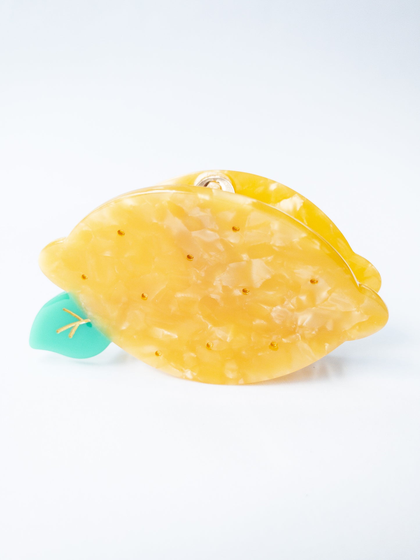 A happy yellow lemon hair claw with beautiful flecks, gold dimples, and a green leaf. Nothing brightens up your day like a sunny lemon! This hair claw clip is a medium size, great for half up hairstyles.