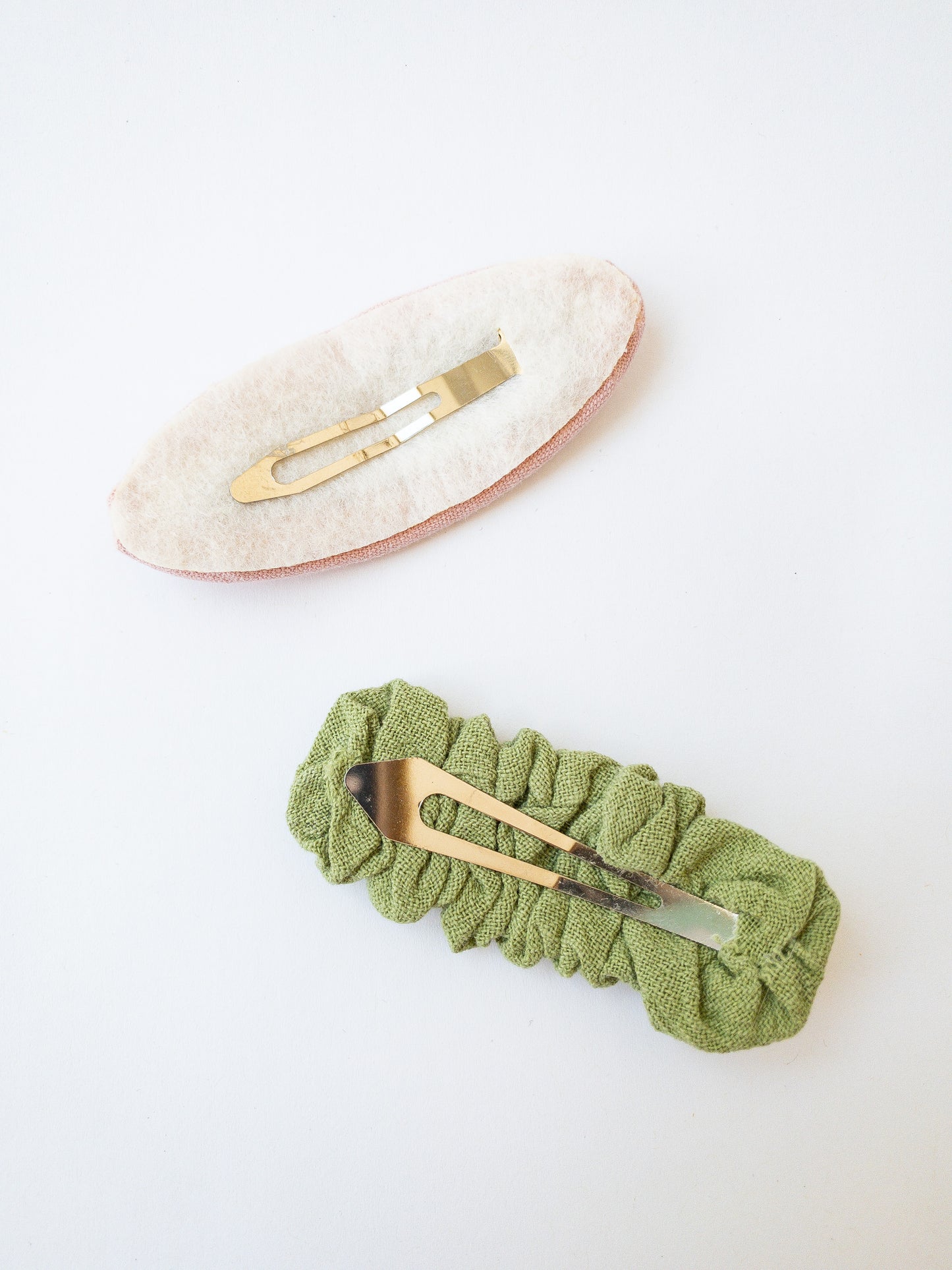 A set of two beautiful fabric wrapped snap clip barrettes. One oval barrette with an embroidered flower and one rectangular ruffled fabric barrette.