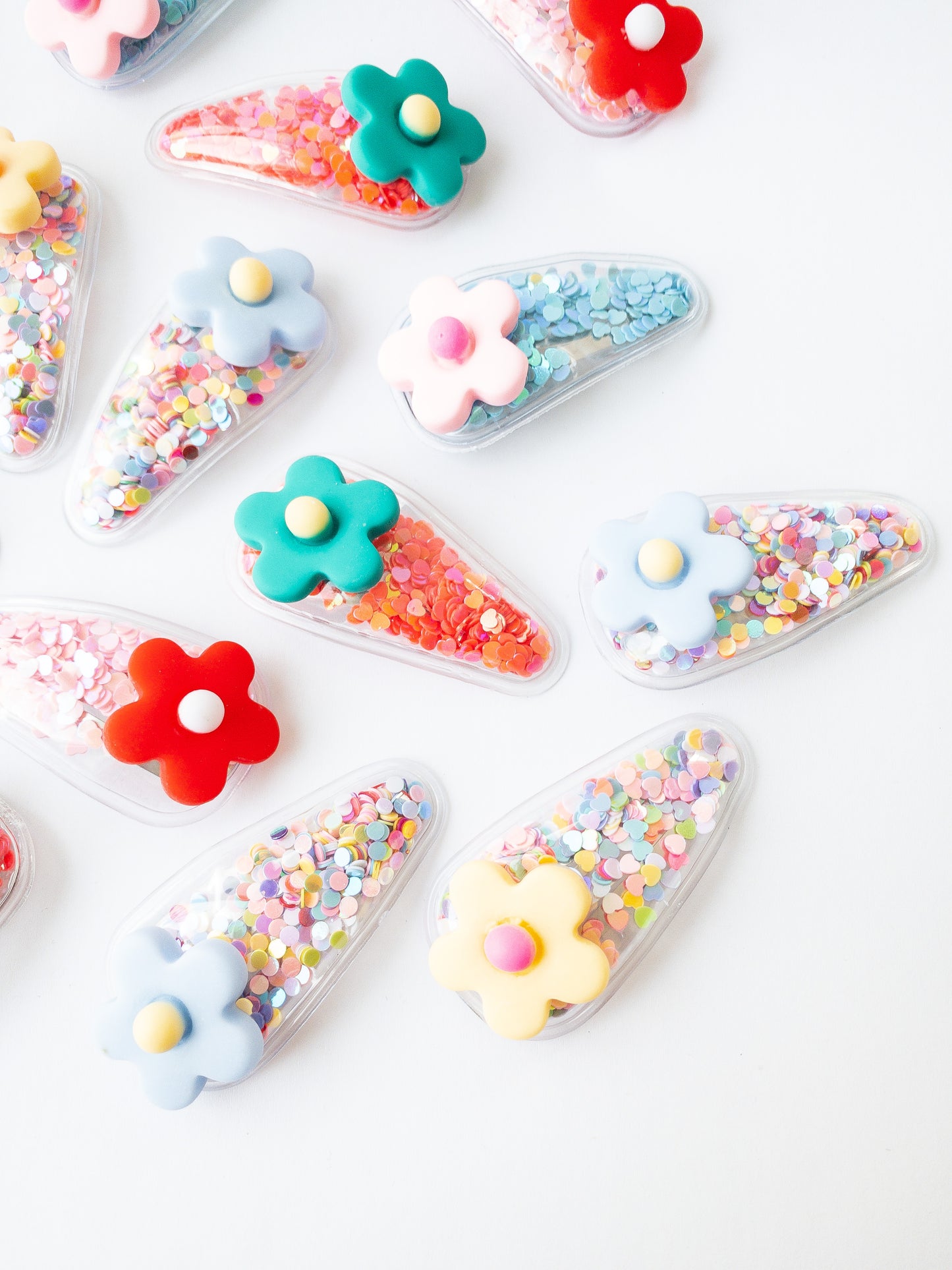 Our signature shaker hair clips but with flowers! Each snap clip is a triangular pouch filled with the most fun confetti--hearts and circles. And to top it all off, there is a pretty flower on the end of each clip. These are sure to make anyone smile!