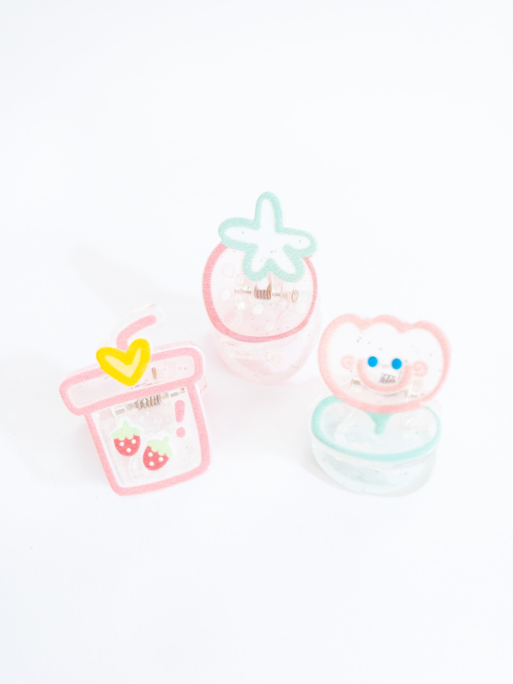 Just a happy tulip and her strawberry treats! A 3-pack of translucent, glittery small hair claws in the shape of a strawberry bubble tea, smiley tulip, and a juicy strawberry.