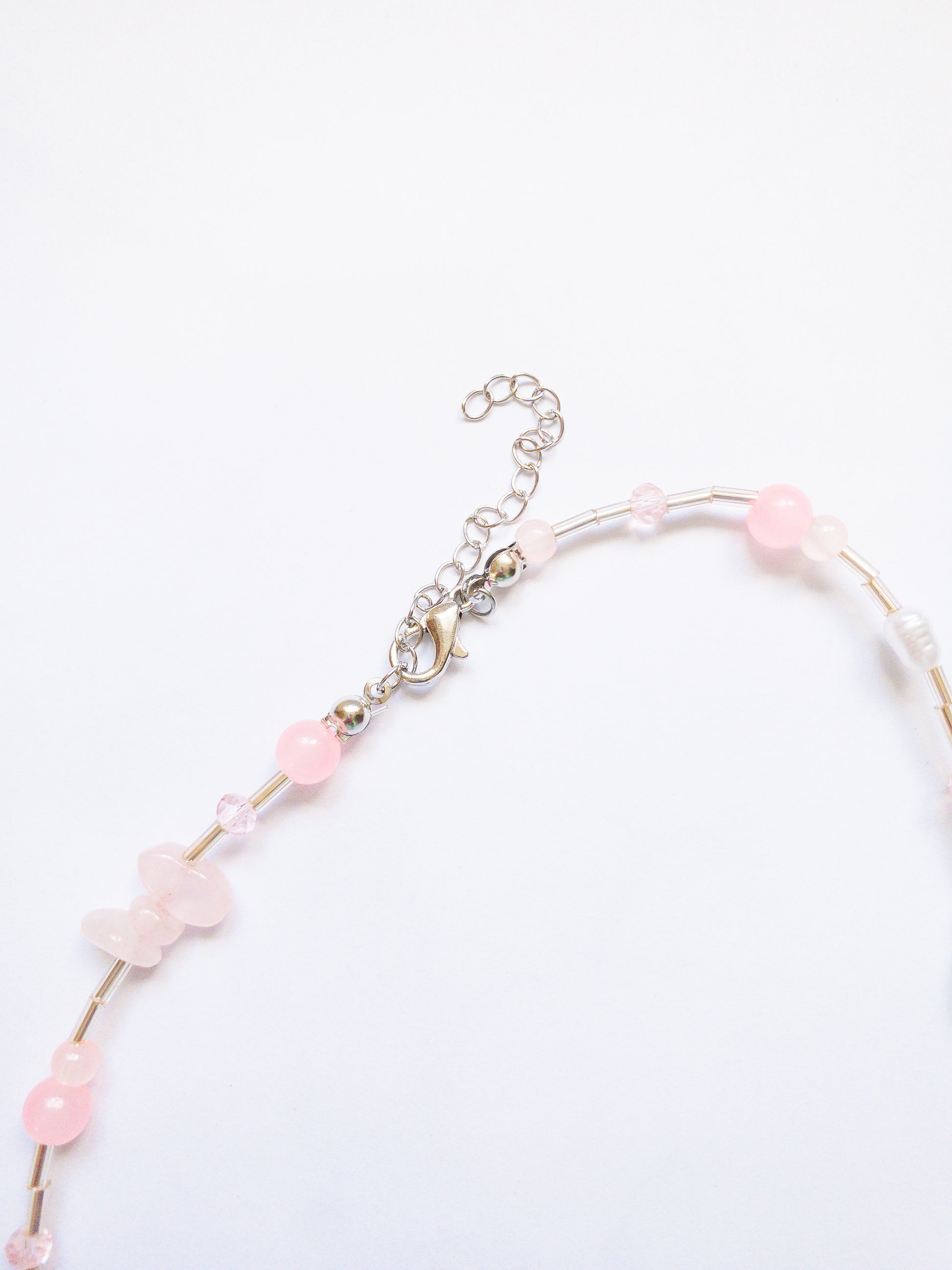 Pretty little beaded bow necklace with light pink and green stones, pearls, and a pink starfish. A subtle and delicate way to add bows to your look.