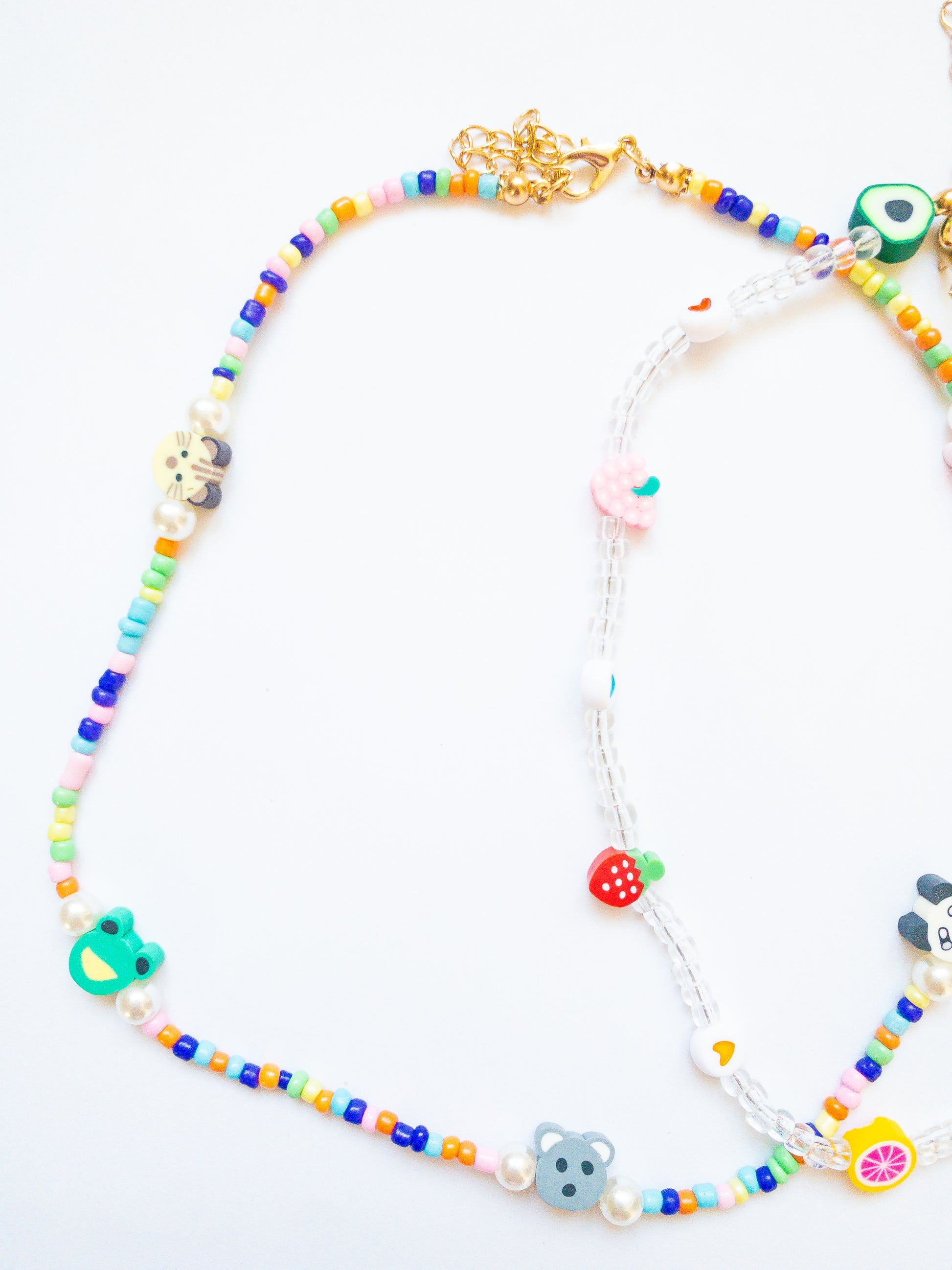 Cutie fruity necklace set! This critter necklace is bright and colorful with a cutie crew of animals and this fruity necklace has clear beads with hearts and juicy fruits. Each necklace is adjustable in length.