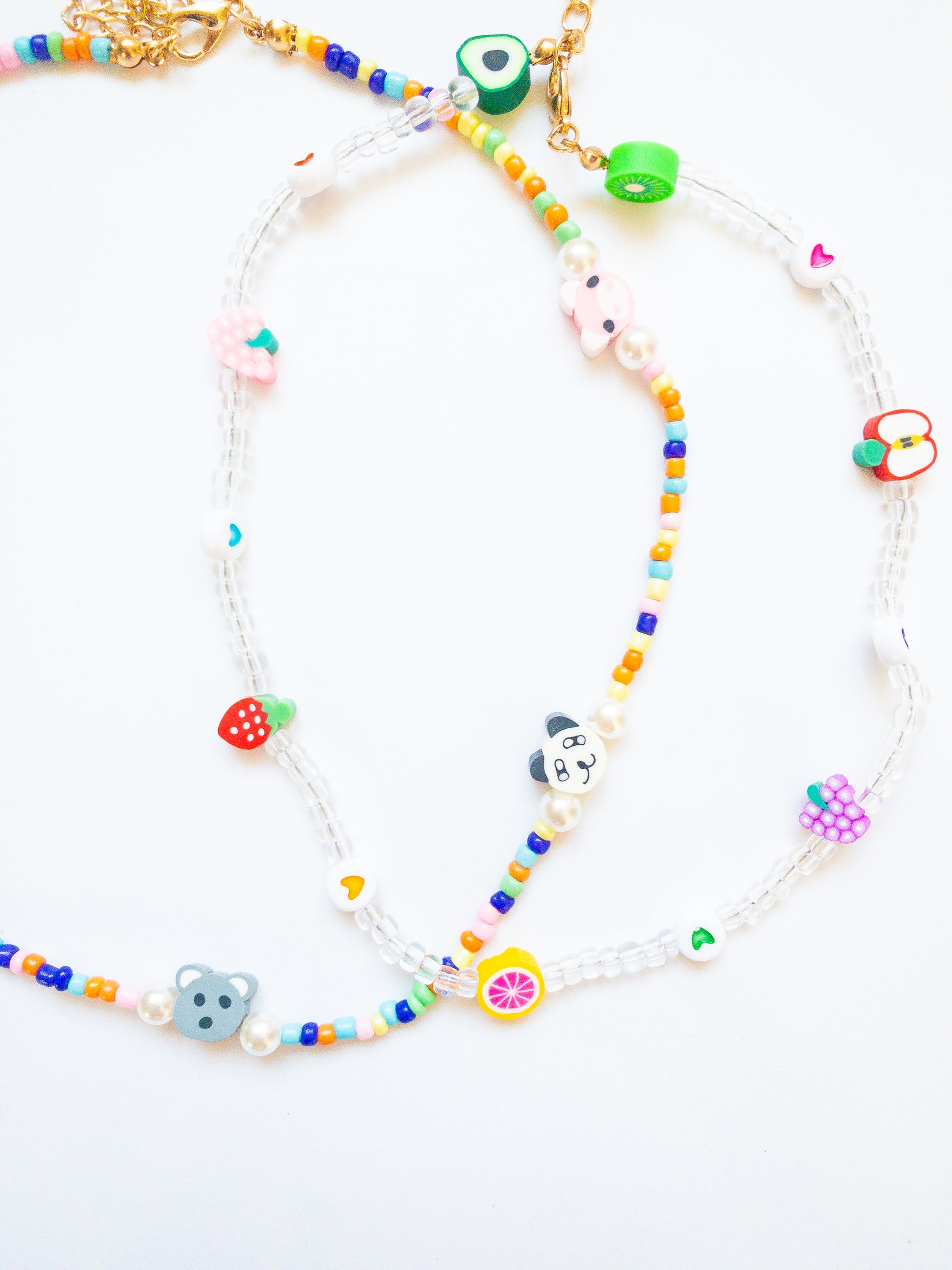 Cutie fruity necklace set! This critter necklace is bright and colorful with a cutie crew of animals and this fruity necklace has clear beads with hearts and juicy fruits. Each necklace is adjustable in length.