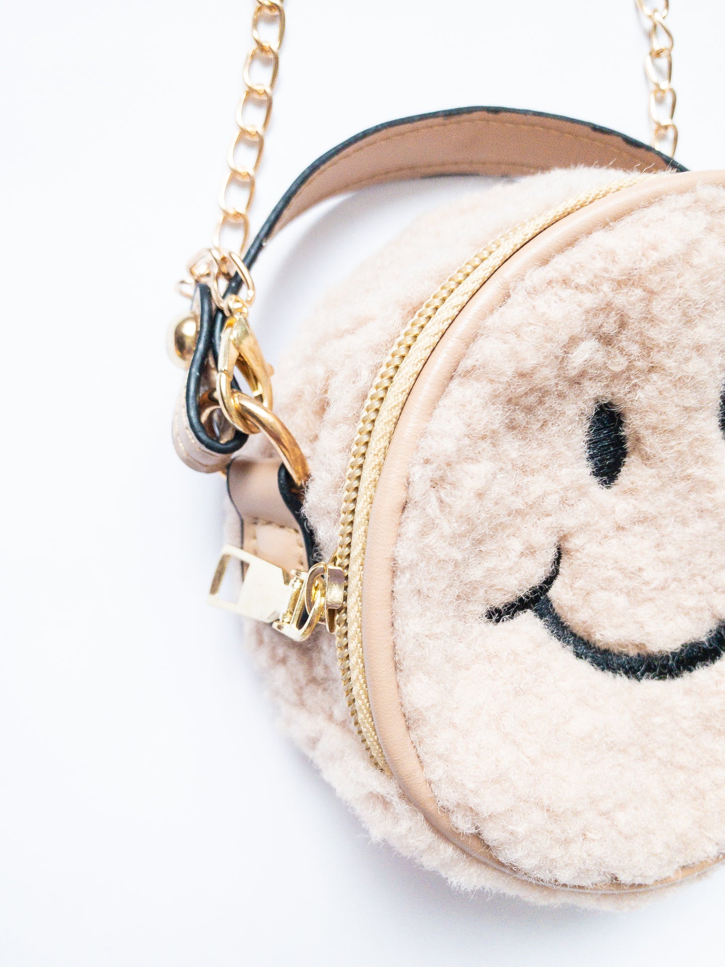 The cutest smiley face bag! This little purse is fuzzy and happy with a single zip open. It has a small open pocket in the back and a short vegan leather handle. The gold chain strap is removable. Choose from 3 cute colors.