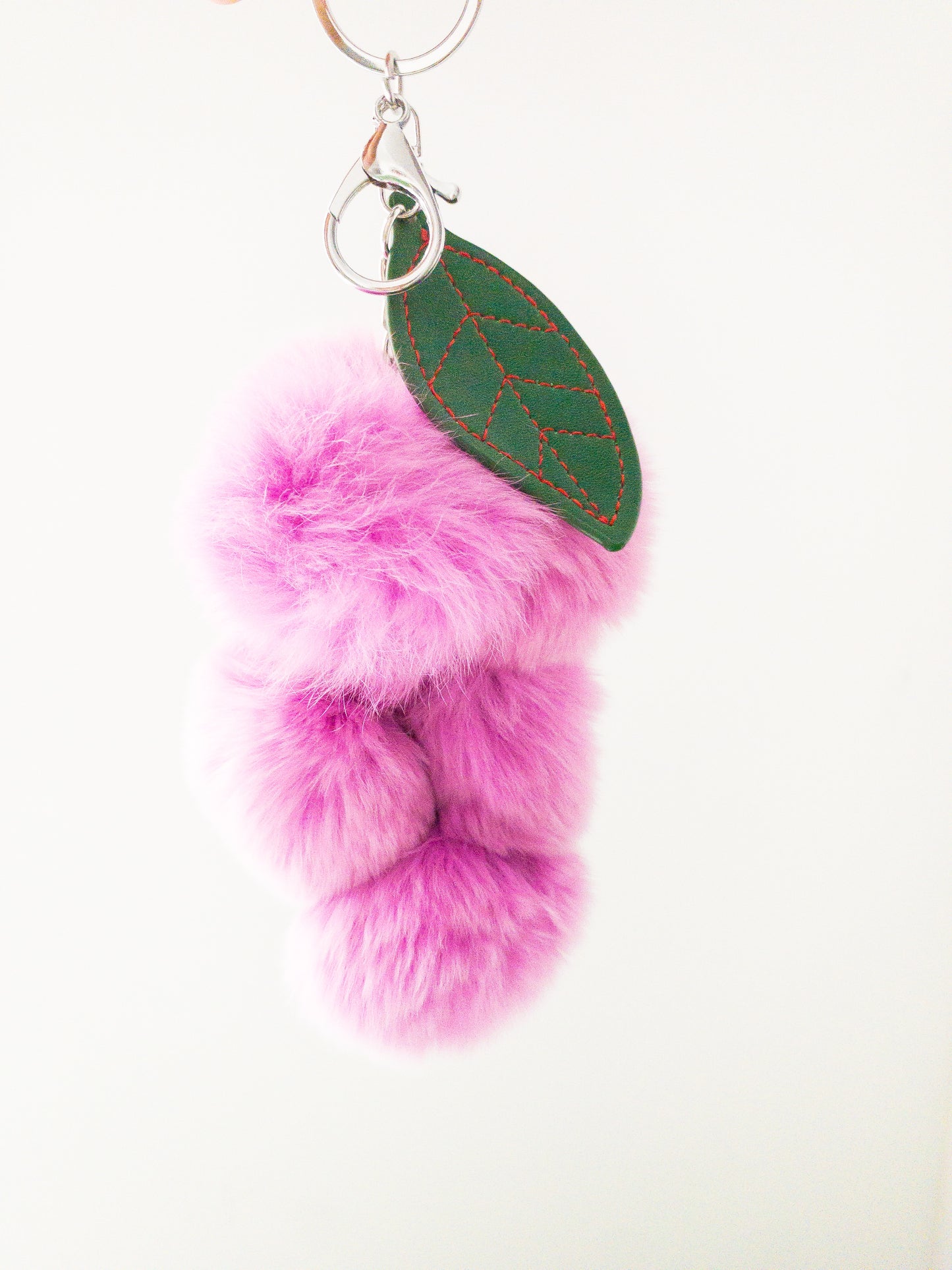 Add a pop of fun to your keys with this super soft grape keychain! The faux rabbit fur is addictively soft and strung together on a chain with a vegan leather grape petal. Clip onto your purse or backpack or attach your keys, making them easy to find at the bottom of your bag.