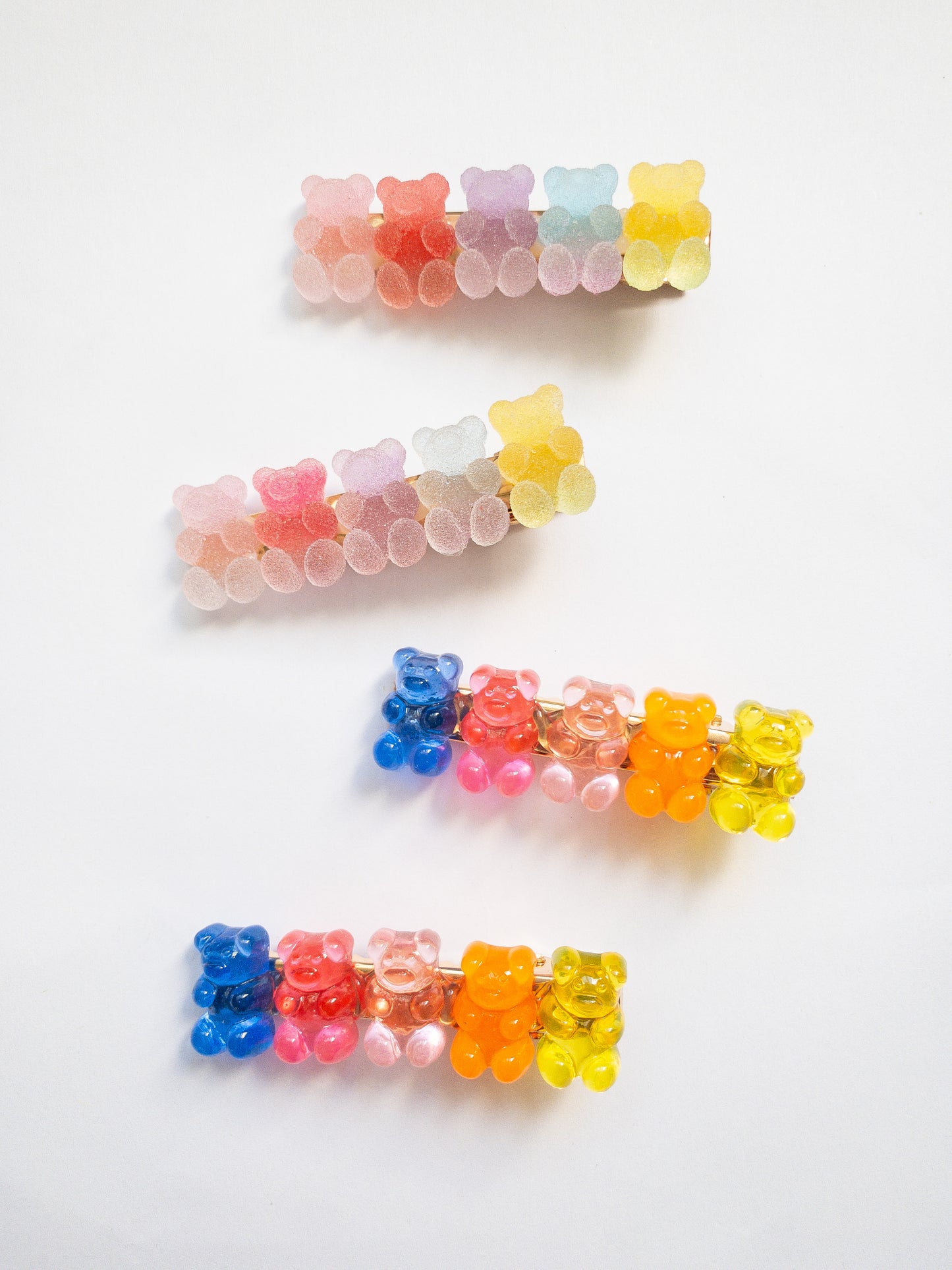 Yummy gummy bear family! The most adorable gummy bear shaped hair clips come as a 4 piece set: two frosted, sugary gummy bears and two translucent rainbow colored gummy bears. Each is on a gold colored alligator clip. 