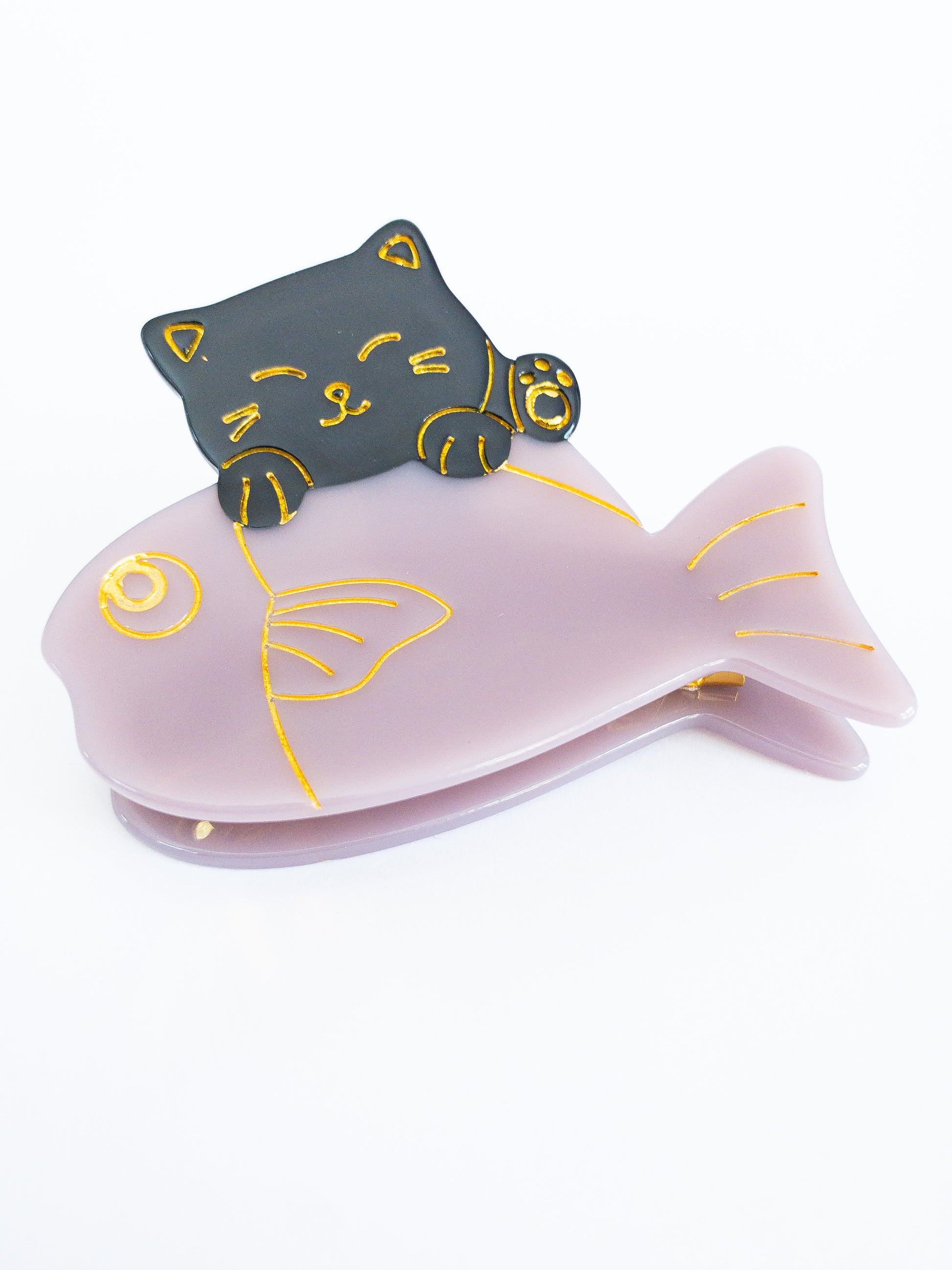 Lucky cat catches a shiny fish! This strong and sturdy cellulose acetate and pretty metal gold hair claw is the cutest way to hold your hair up. The lucky cat and the shiny light purple fish is outlined in a beautiful gold glimmer adding a gorgeous detail.