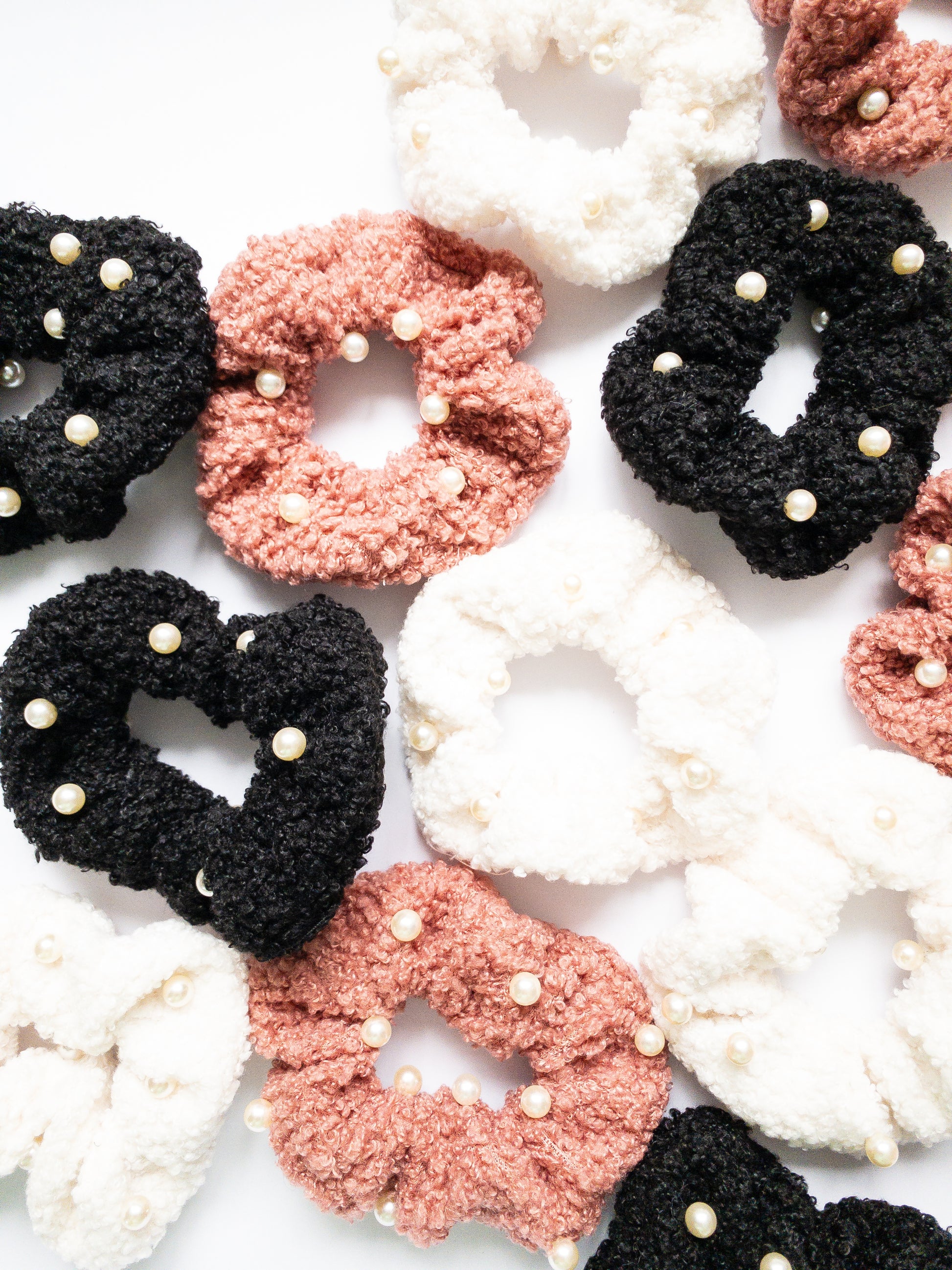These peppy pearl sherpa scrunchies are so soft and comfy chic! A 3-pack mix of pink, black, and white sherpa and pearls sewn throughout. 