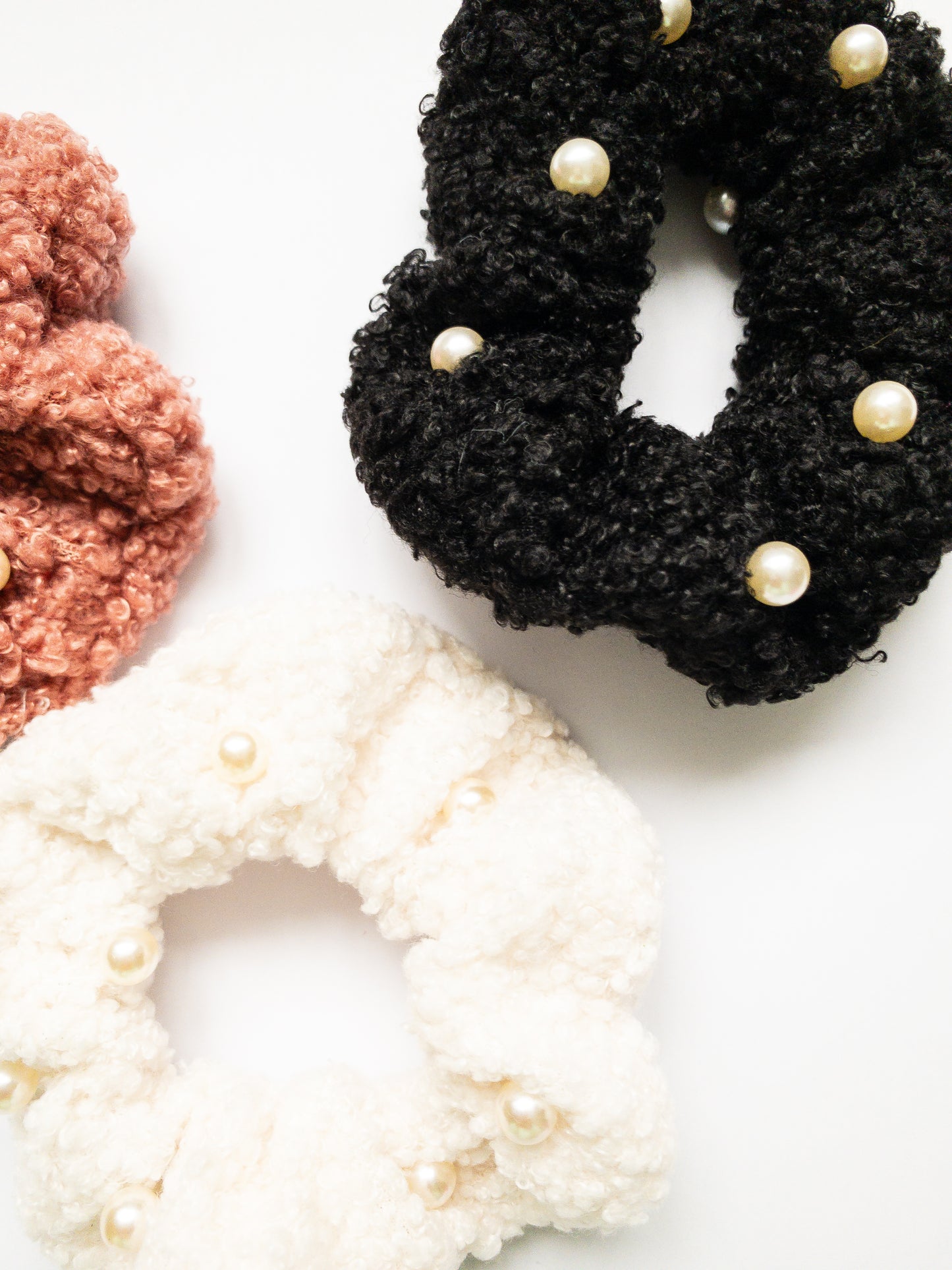 These peppy pearl sherpa scrunchies are so soft and comfy chic! A 3-pack mix of pink, black, and white sherpa and pearls sewn throughout. 