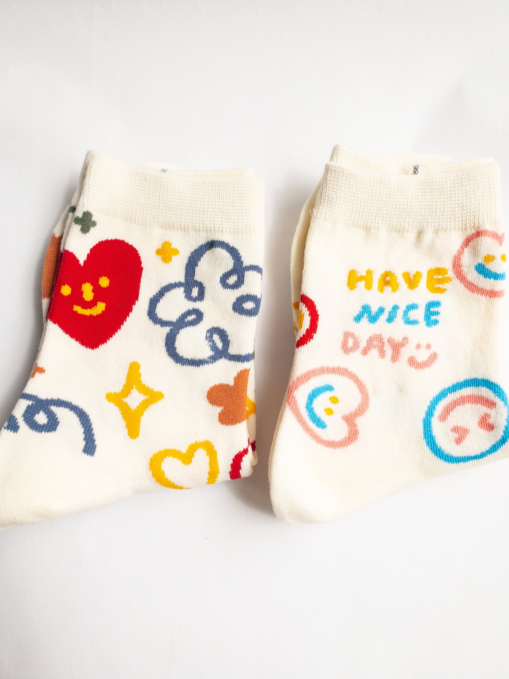 Playful and doodly Have a Nice Day socks! These thick, cozy, and comfortable crew socks feature a cheerful doodle smiley face and flower design, sure to put a smile on your face and a spring in your step every day. 