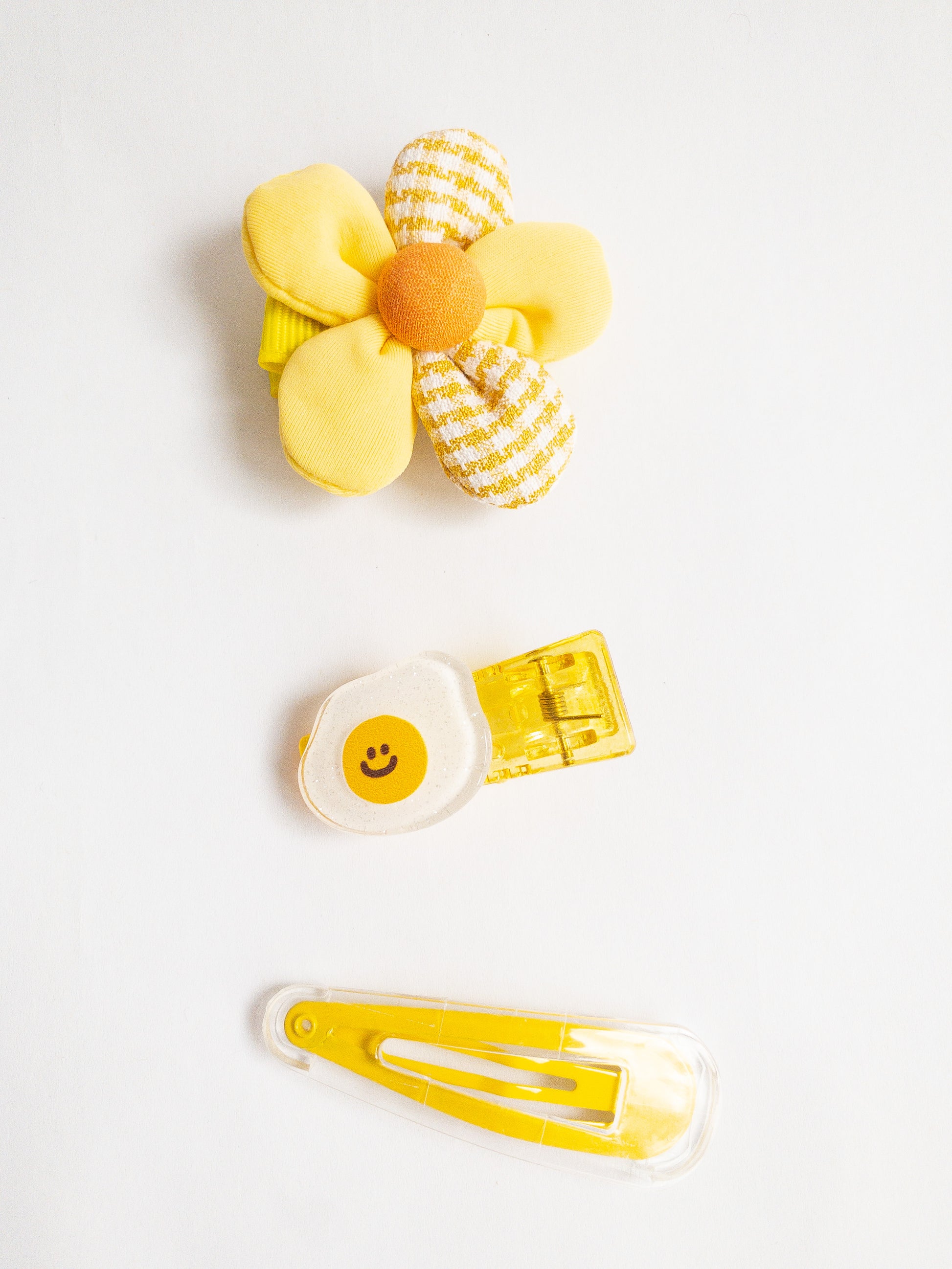 Take your hair from blah to yum with this 3-piece Happy Eggy hair clip set! Adorably decorated with a glitter fried egg, a fabric flower, and a clear/yellow snap clip. 