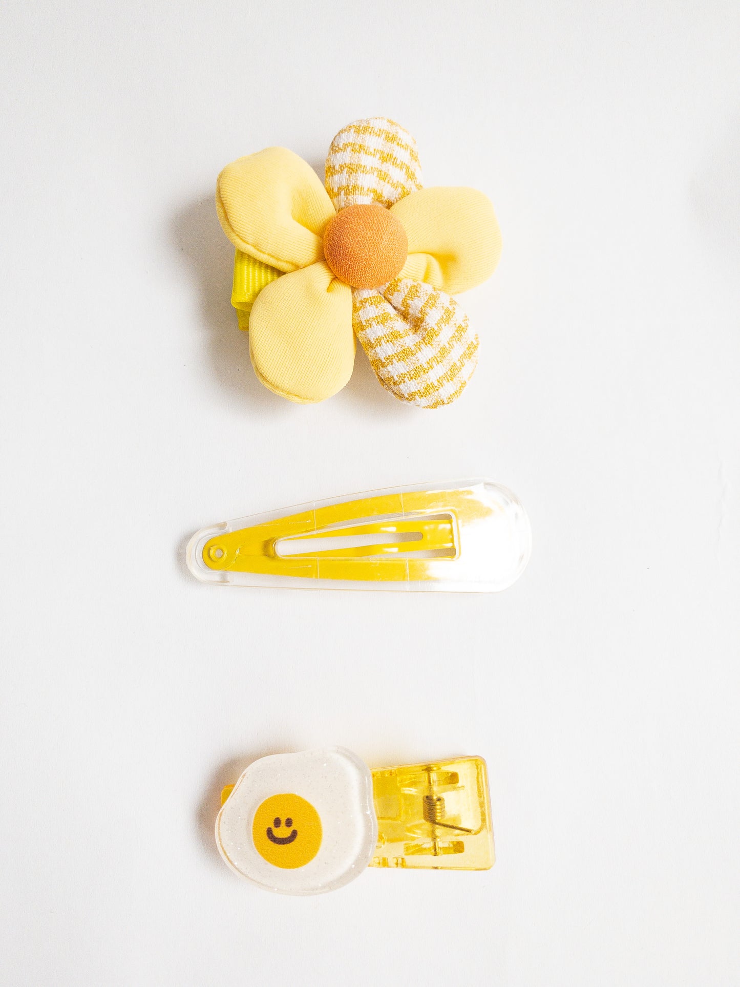 Take your hair from blah to yum with this 3-piece Happy Eggy hair clip set! Adorably decorated with a glitter fried egg, a fabric flower, and a clear/yellow snap clip. 