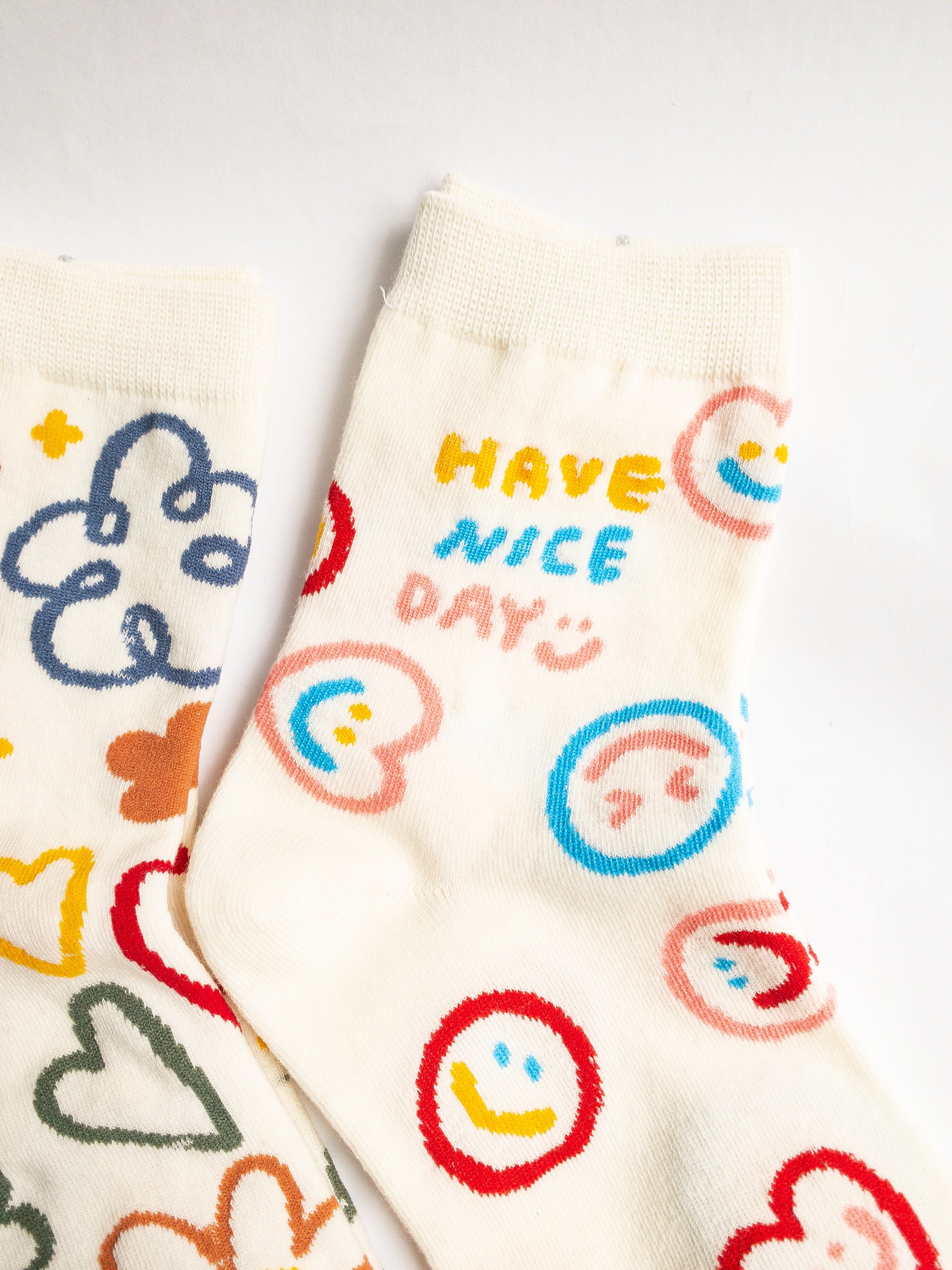 Playful and doodly Have a Nice Day socks! These thick, cozy, and comfortable crew socks feature a cheerful doodle smiley face and flower design, sure to put a smile on your face and a spring in your step every day. 