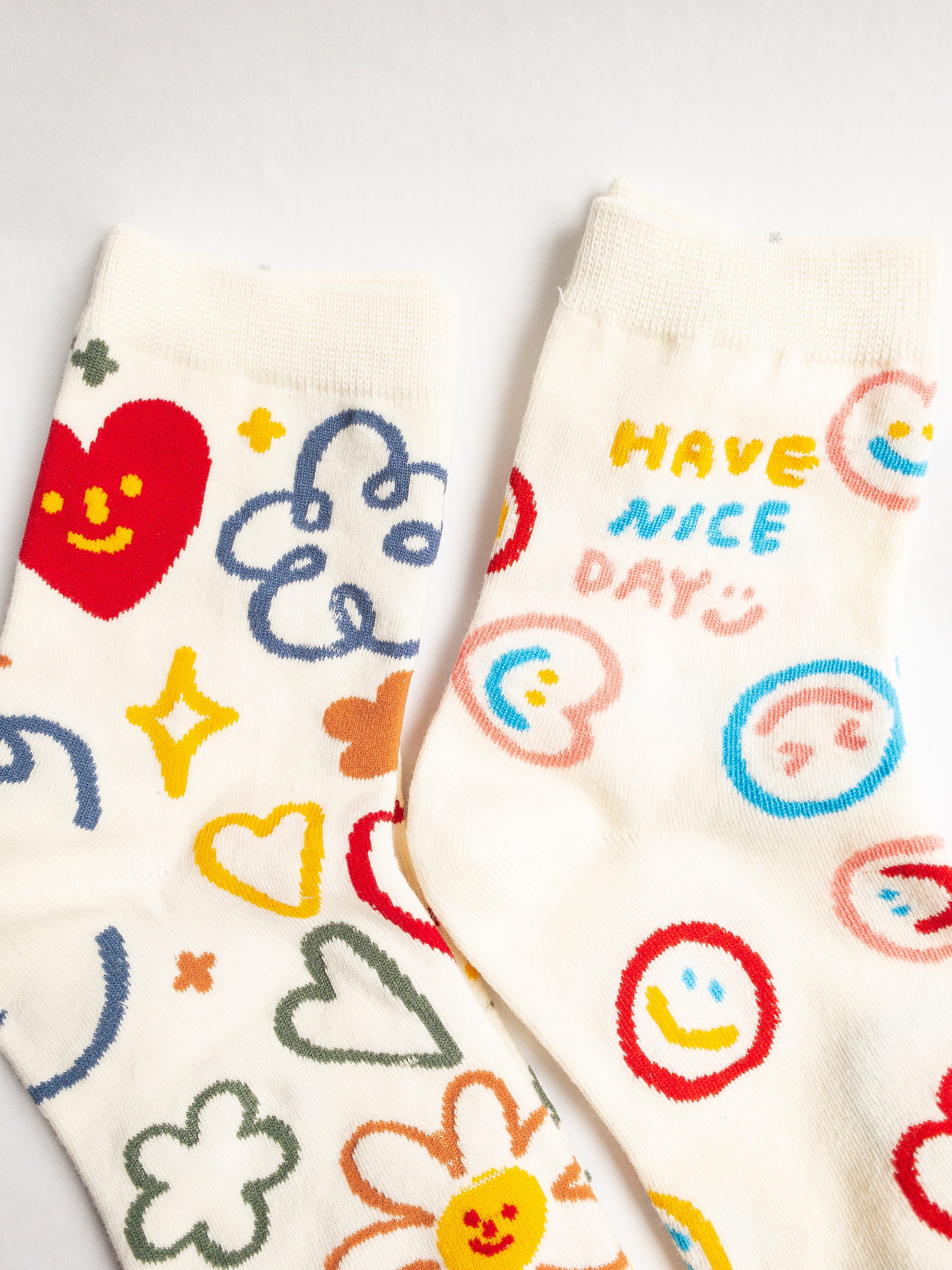 Playful and doodly Have a Nice Day socks! These thick, cozy, and comfortable crew socks feature a cheerful doodle smiley face and flower design, sure to put a smile on your face and a spring in your step every day. 