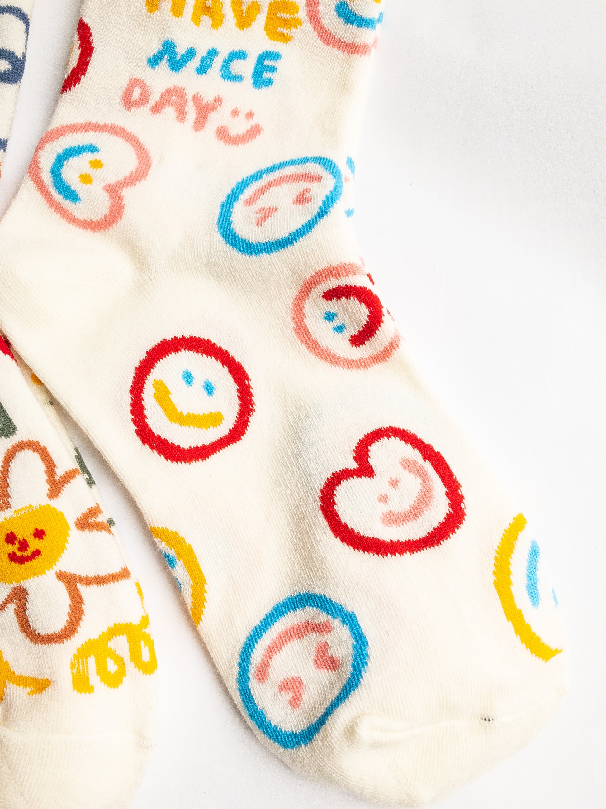 Playful and doodly Have a Nice Day socks! These thick, cozy, and comfortable crew socks feature a cheerful doodle smiley face and flower design, sure to put a smile on your face and a spring in your step every day. 