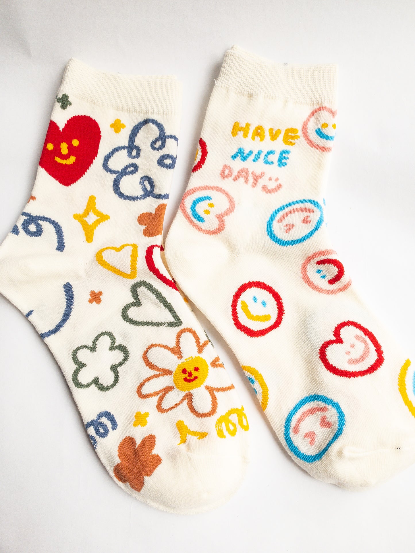 Playful and doodly Have a Nice Day socks! These thick, cozy, and comfortable crew socks feature a cheerful doodle smiley face and flower design, sure to put a smile on your face and a spring in your step every day. 