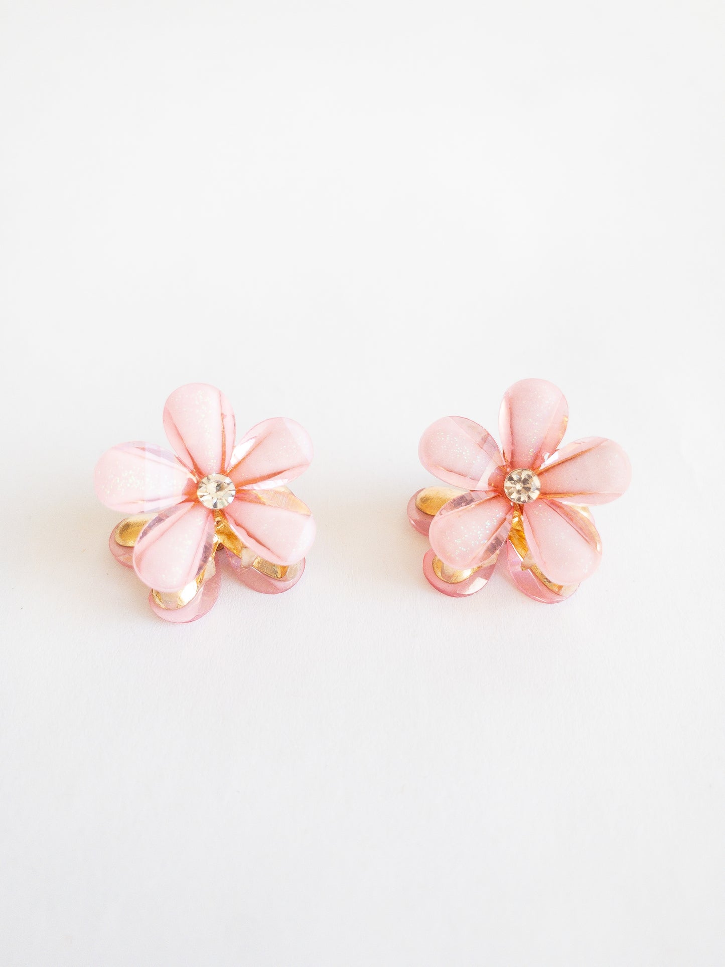 Dazzling small flower hair claws with a subtle glittery shimmer and a pretty white gemstone in the center. Each set has two flower claws to pair up in your favorite styles.