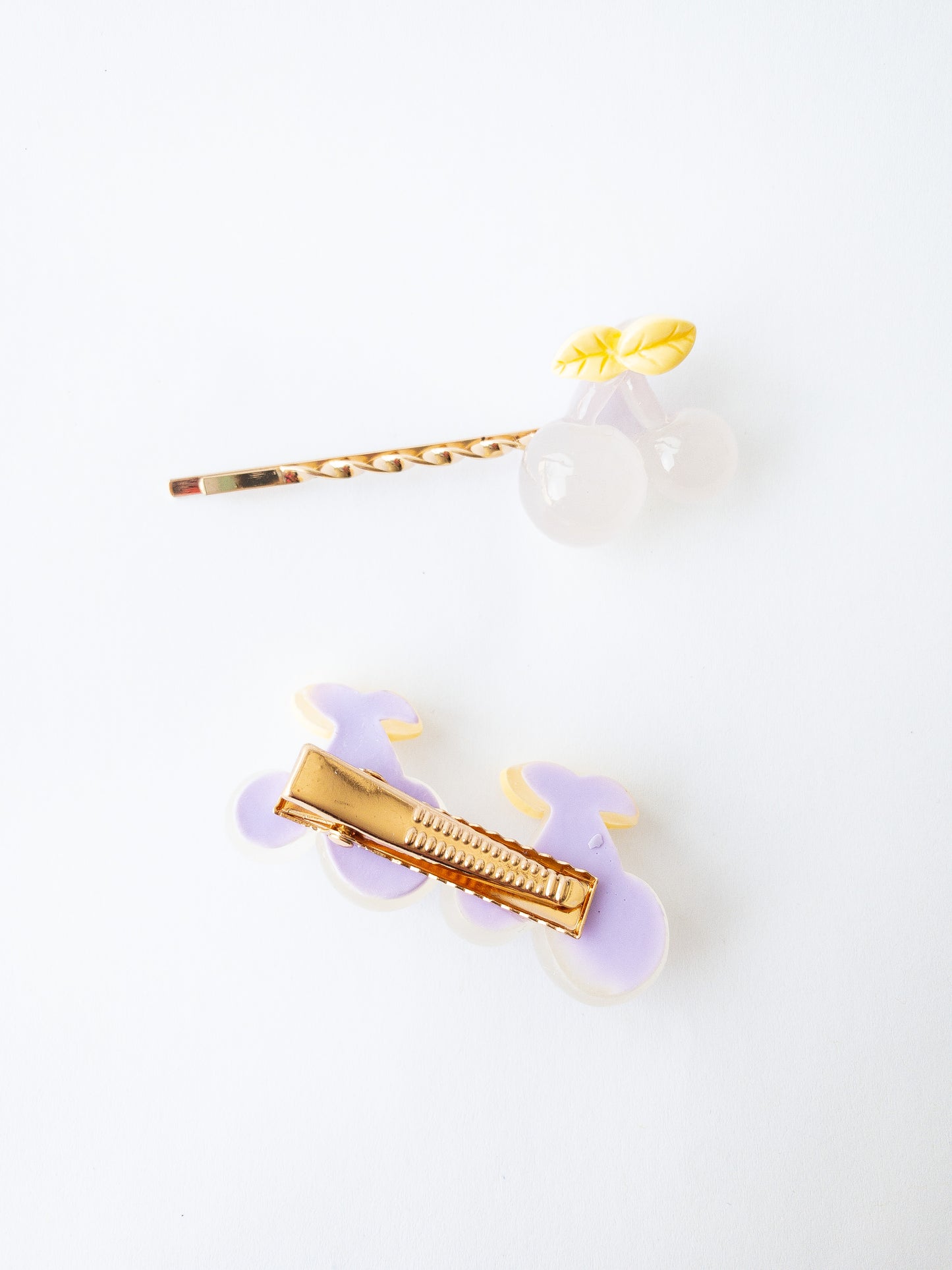 Milky jelly cherries with a pretty purple tint. Two sets of cherries on a small alligator clip and one set of cherries on a beautiful twisted gold bobby pin. 