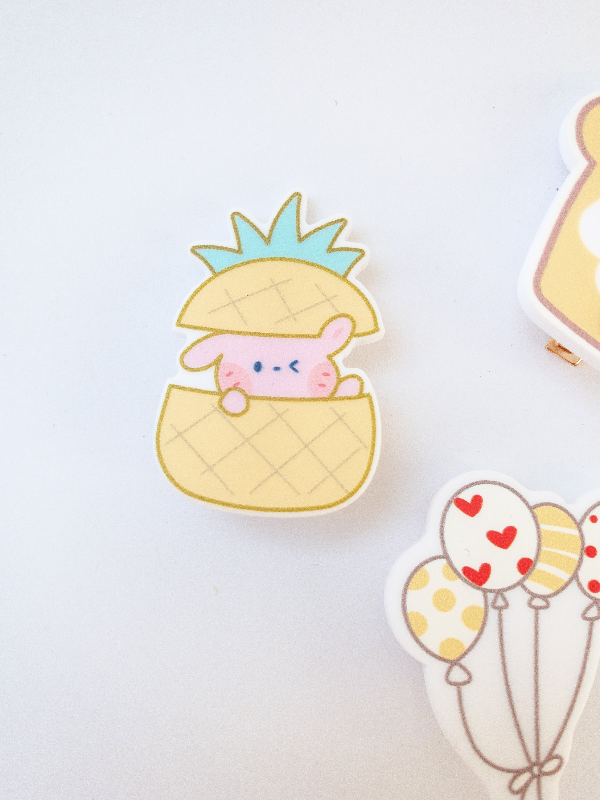 A set of 3 yellow hair clips in the sweetest shapes. A little pink bunny hidden inside a pineapple, a set of balloons, and a delicious strawberry toast.  Gold alligator clips