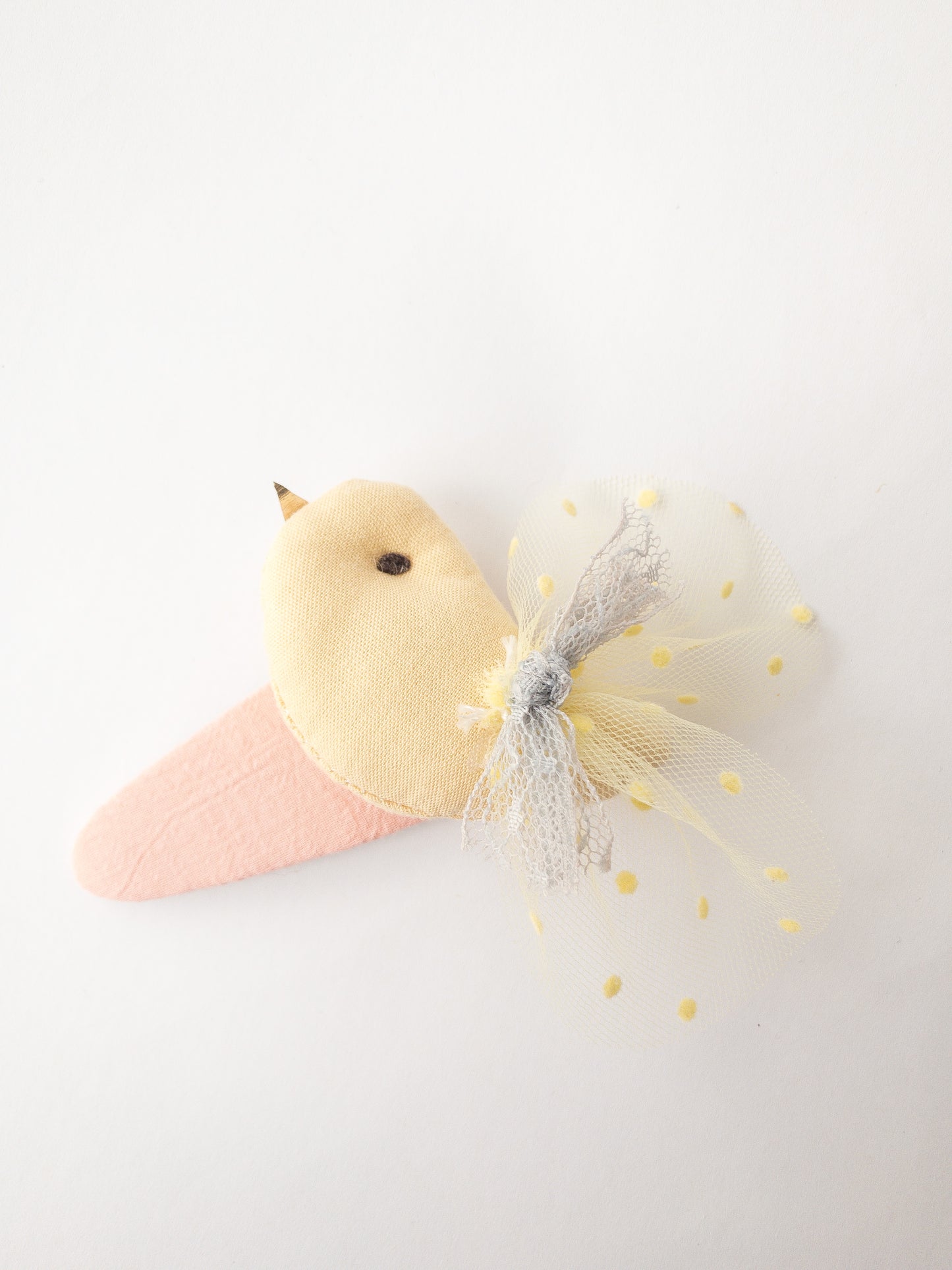 The sweetest plush bird in hair clip form! This snap clip is covered in fabric and decorated with a cute plush bird which has lace wings, a little lace bow, a stitched eye and metallic fabric beak. There really is no cuter hair clip!