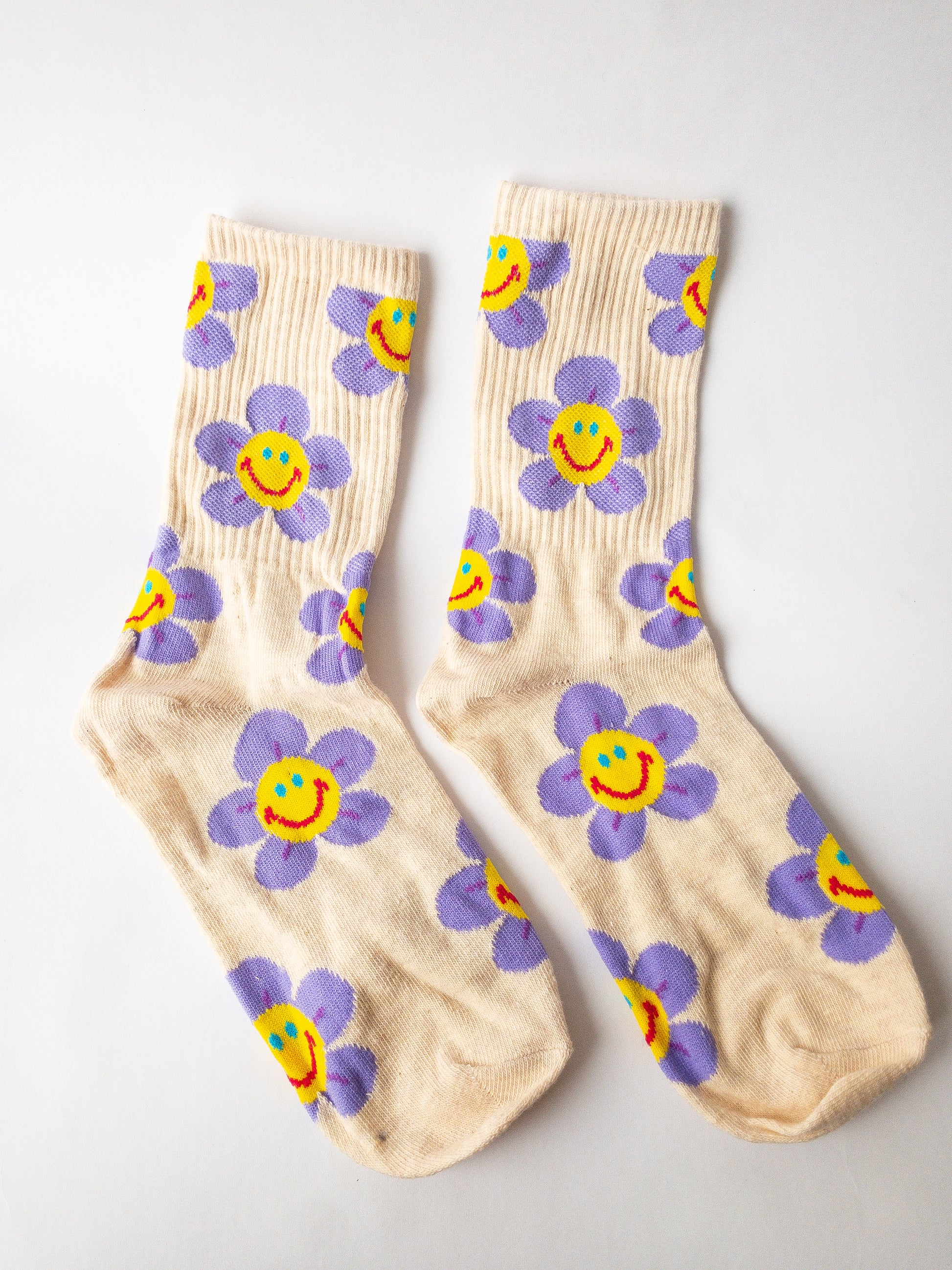 Groovy, happy and cute! Two pairs of crew length socks in this set with one pair being light purple with bright pink smiley flowers and the other being a cream color with purple smiley flowers.  Adult size 4-10, crew socks length.