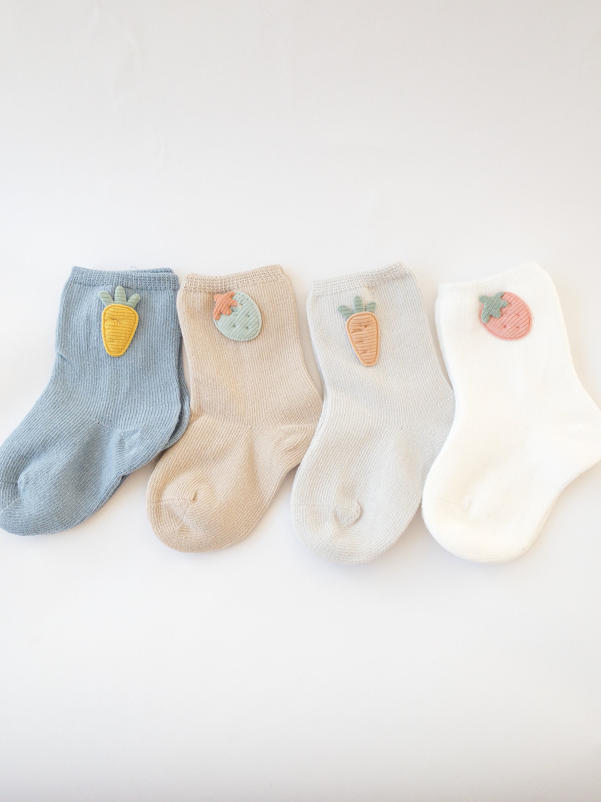 Our love for fruit continues with these socks adorned with cute fabric strawberries and carrots. Each set comes with 4 pairs of socks. Choose from two colorways: pink/yellow/grey/white or blue/grey/taupe/white.