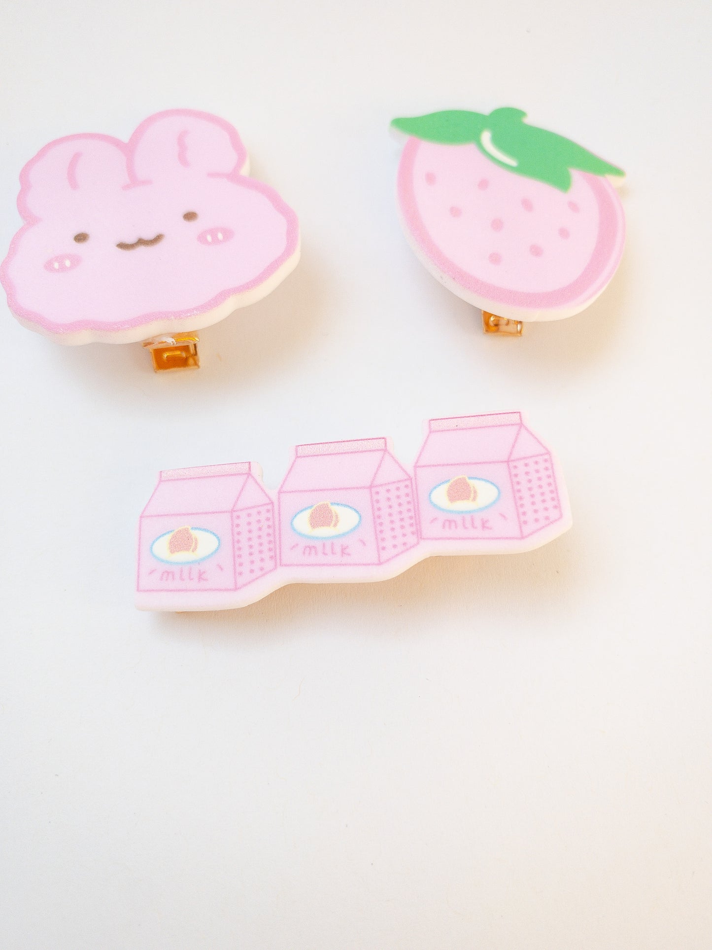 A set of 3 pink hair clips in the sweetest shapes. A pink fluffy cartoon bunny, a big juicy strawberry, and a trio of strawberry milks.  Gold alligator clips