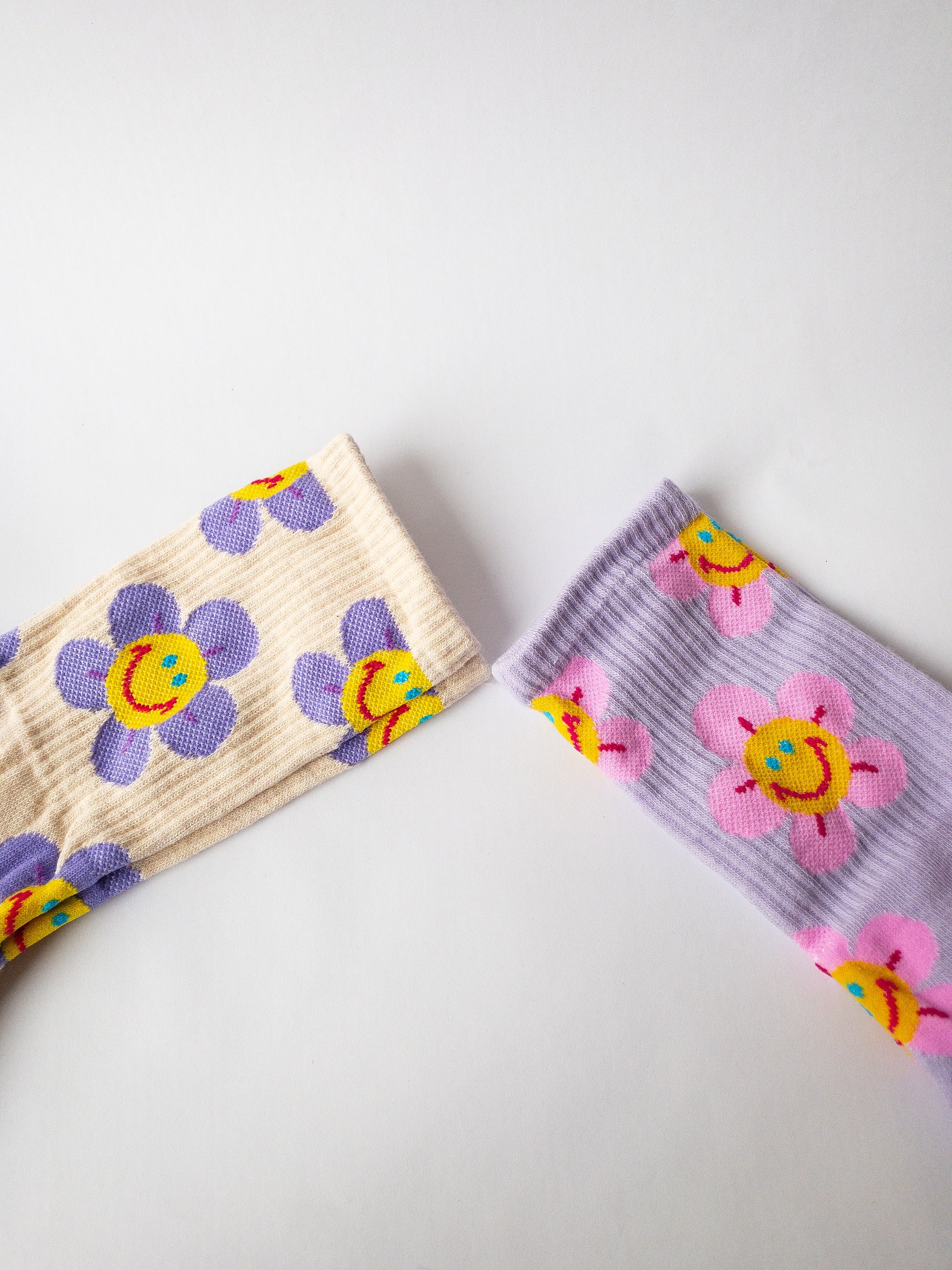 Groovy, happy and cute! Two pairs of crew length socks in this set with one pair being light purple with bright pink smiley flowers and the other being a cream color with purple smiley flowers.  Adult size 4-10, crew socks length.