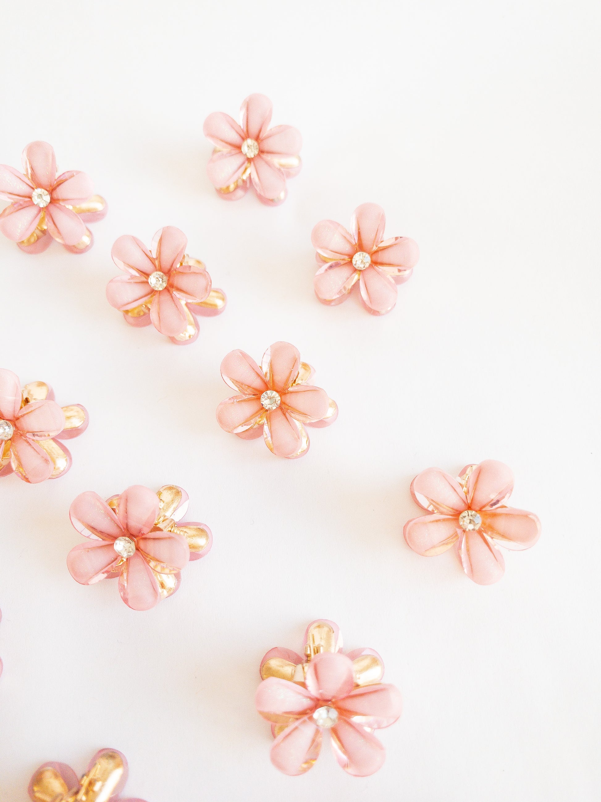 Dazzling small flower hair claws with a subtle glittery shimmer and a pretty white gemstone in the center. Each set has two flower claws to pair up in your favorite styles.