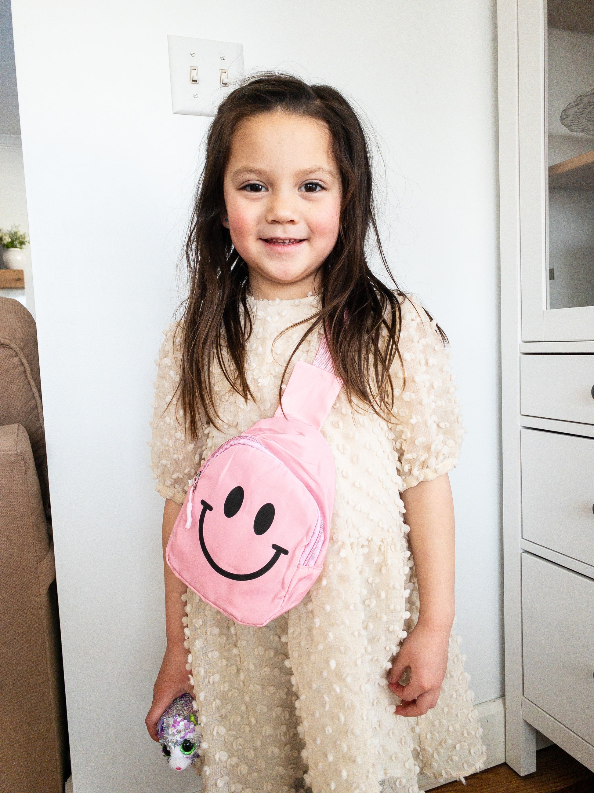 Just a slice of instant happiness. This cute smiley face crossbody or slingback bag is the perfect size for kids. It has a cable cord pull zipper which opens up to a single compartment and is super lightweight with adjustable straps. Wear it front or back.