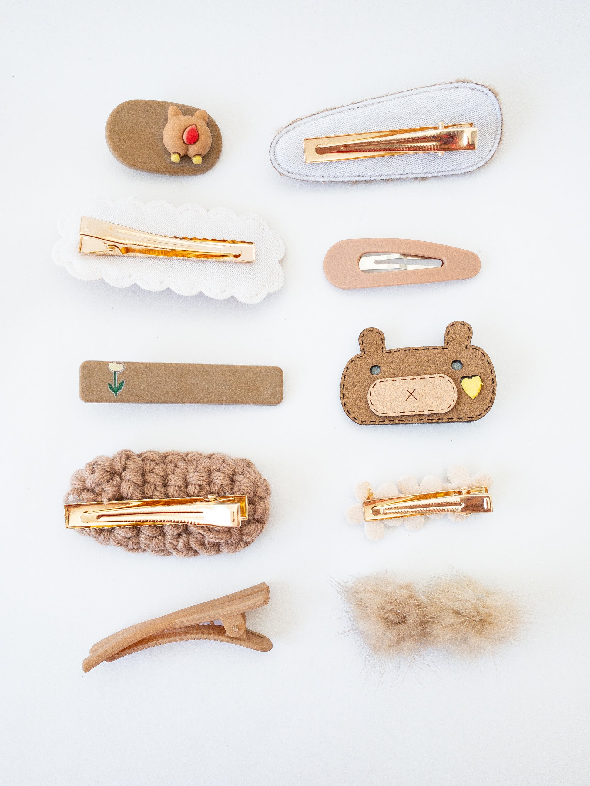 The ultimate set with both cute and classic pieces! There are a total of 10 hair clips in this set. A criss corss alligator clip, an oval crocheted nest, a loving brown bear, a sherpa clip with a soft brown heart, rabbit fur pom poms, a classic rectangular hair clip with a pretty tulip, an oval alligator clip with the cute backside of a bear, a small hair clip with 3 felt flowers, a triangular snap clip and a rabbit fur triangular hair clip.
