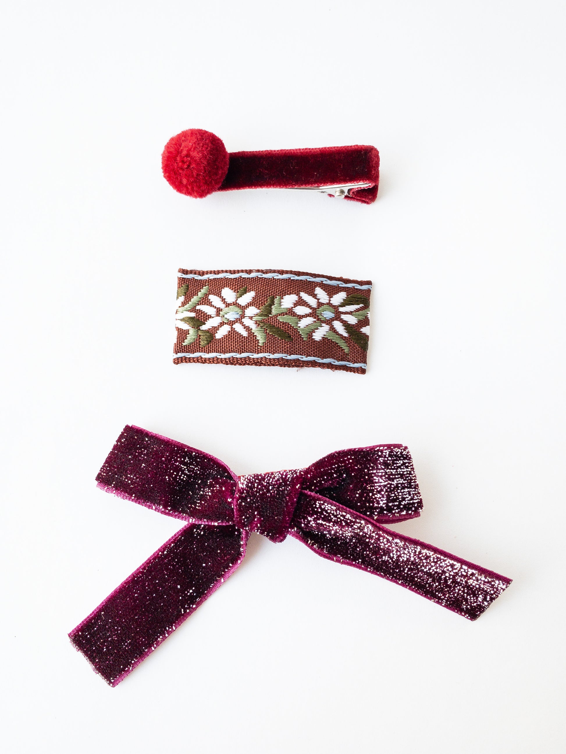 Festive and sparkly, this velvet bow is a classic for any occasion. It comes with a floral fabric wrapped snap clip and a darling velvet pom pom hair clip. Choose from 4 beautiful shades. 